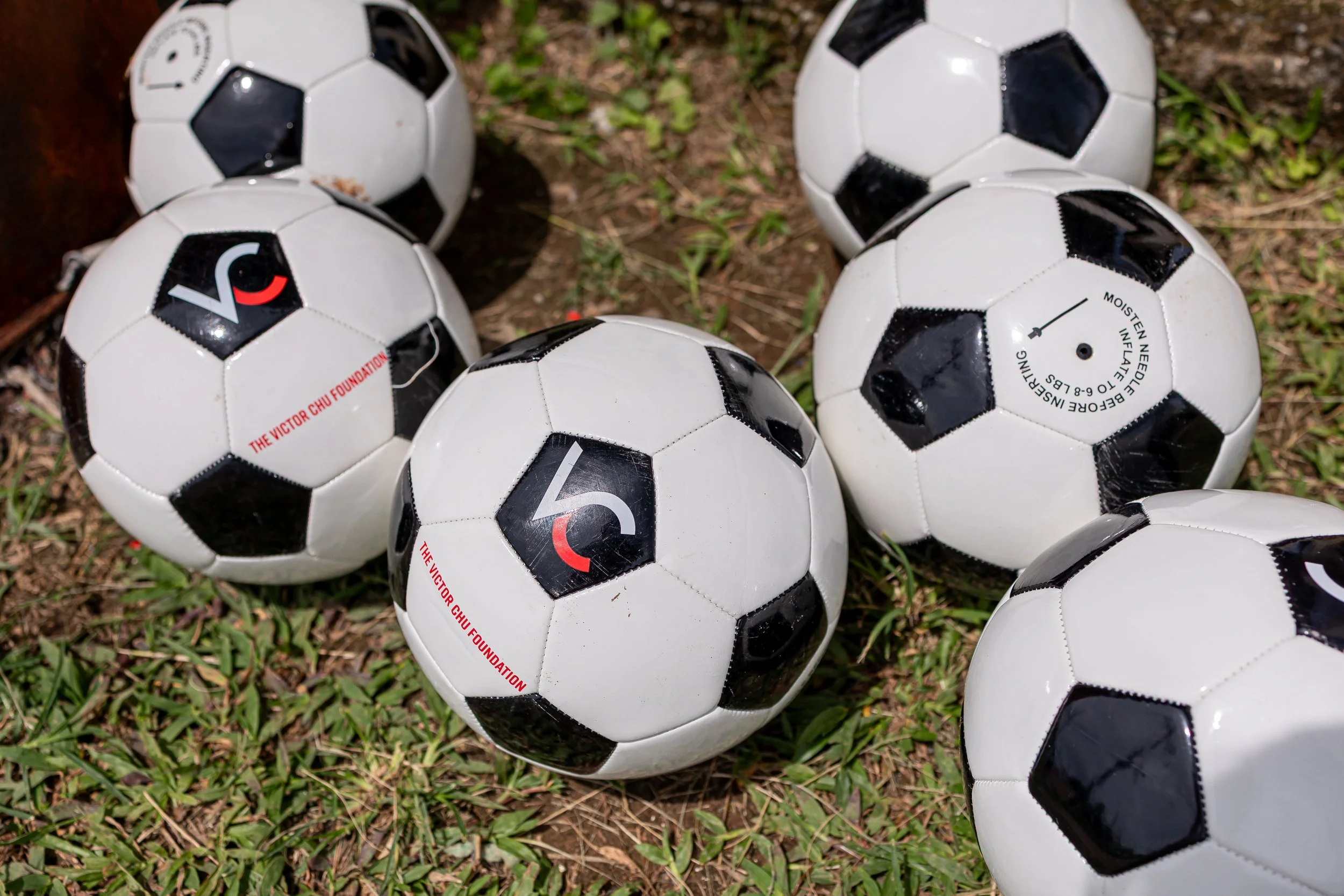 Balones de fútbol sobre hierba y tierra.