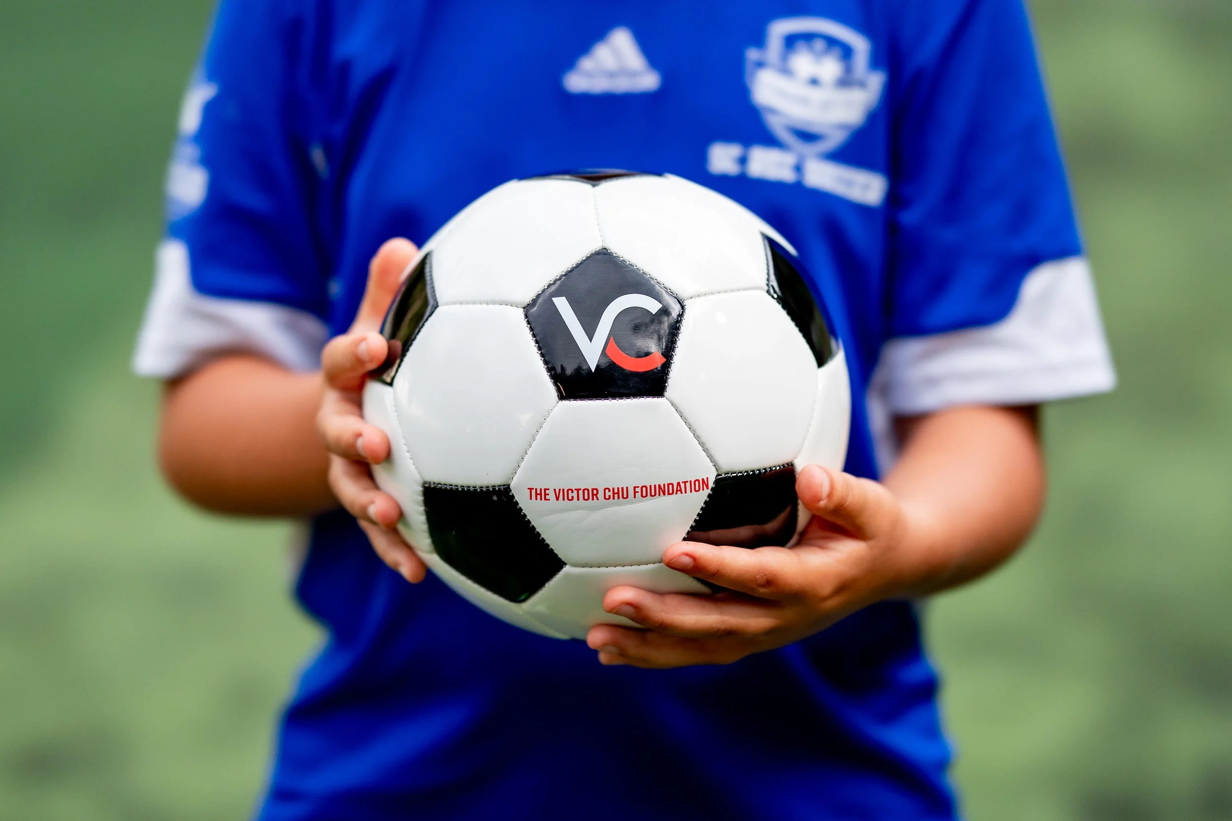 Niño sosteniendo un balón de fútbol con el logo de la Fundación Victor Chu
