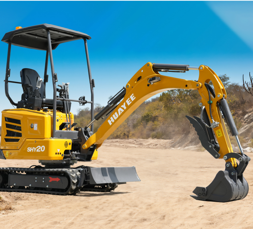 Yellow mini excavator with black track system and hydraulic arm equipped with a digging bucket, working on a sandy outdoor construction site. Clear blue sky in the background.