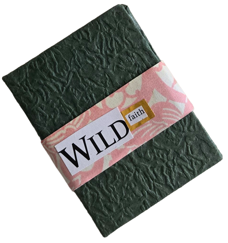 A black textured notebook with a pink and white band that has the words 'WILD faith' on it.
