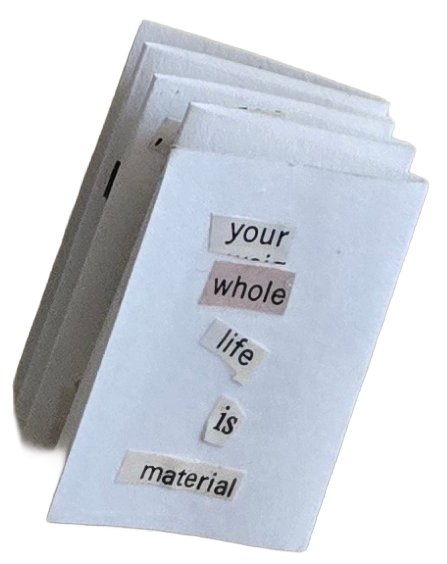 A stack of white paper with a message that reads, "your whole life is material," arranged with cut-out words.