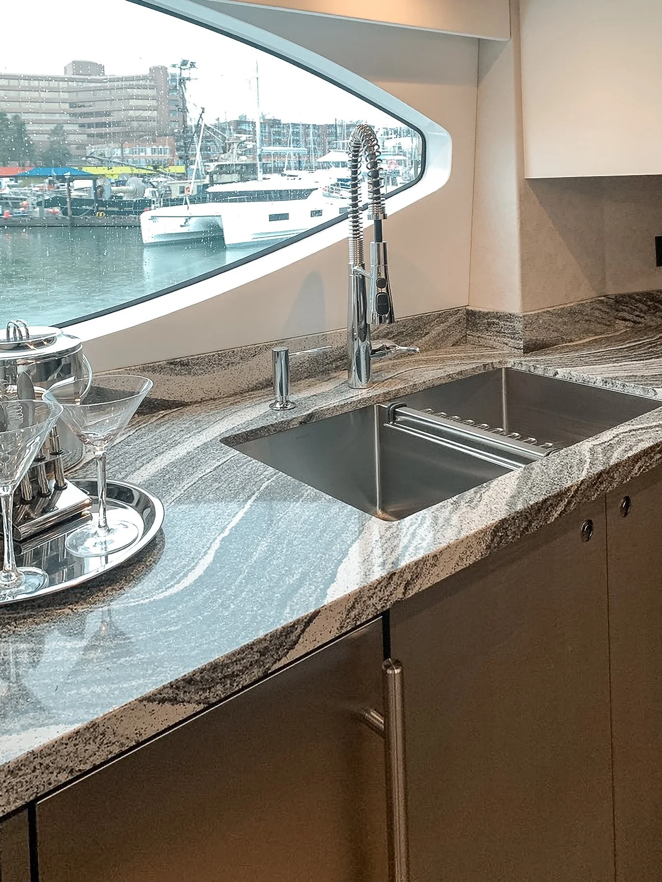 Kitchen with a granite countertop, modern faucet, and a window overlooking a marina with boats.