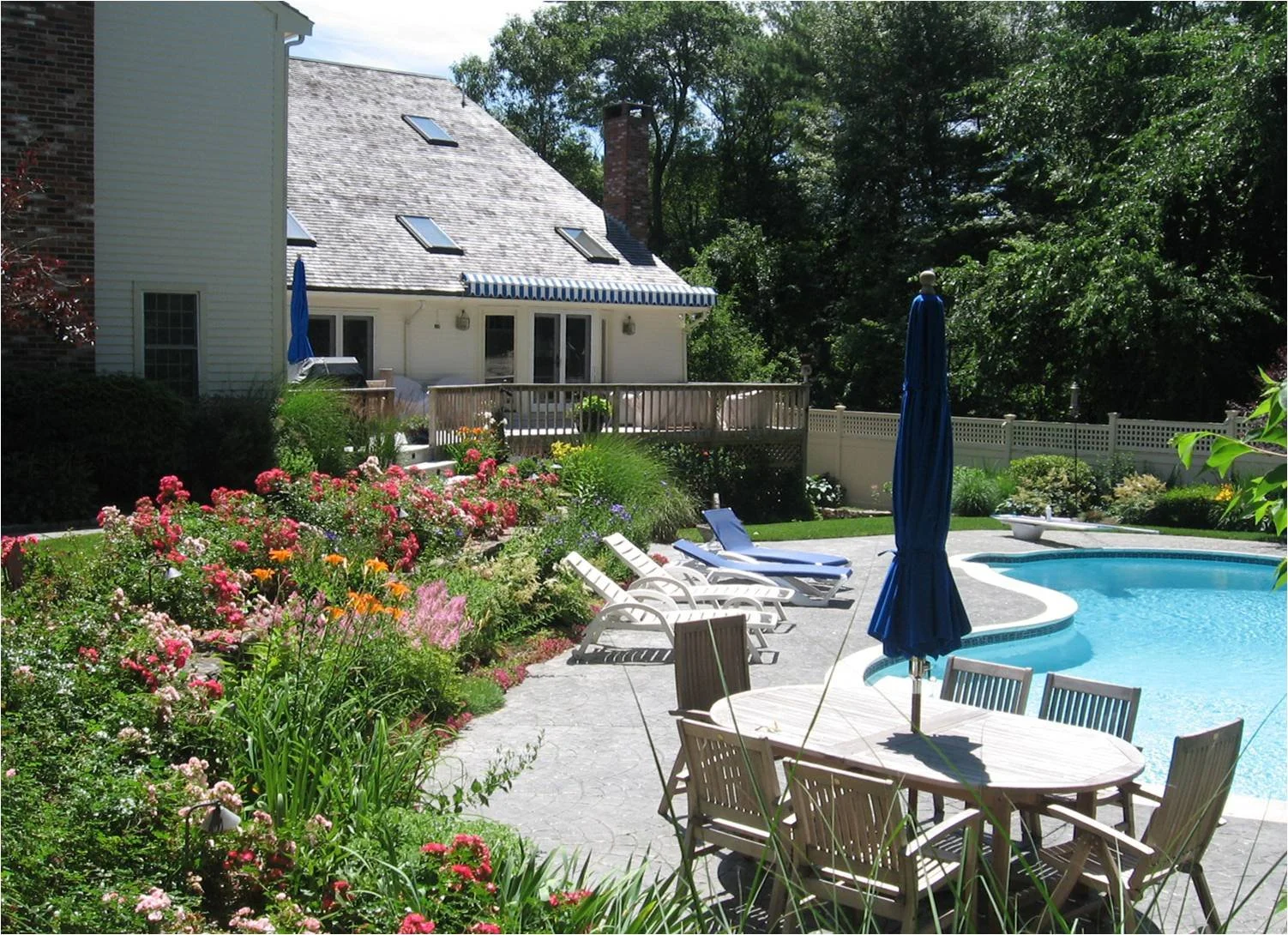 Backyard with swimming pool, patio furniture, and colorful garden flowers.