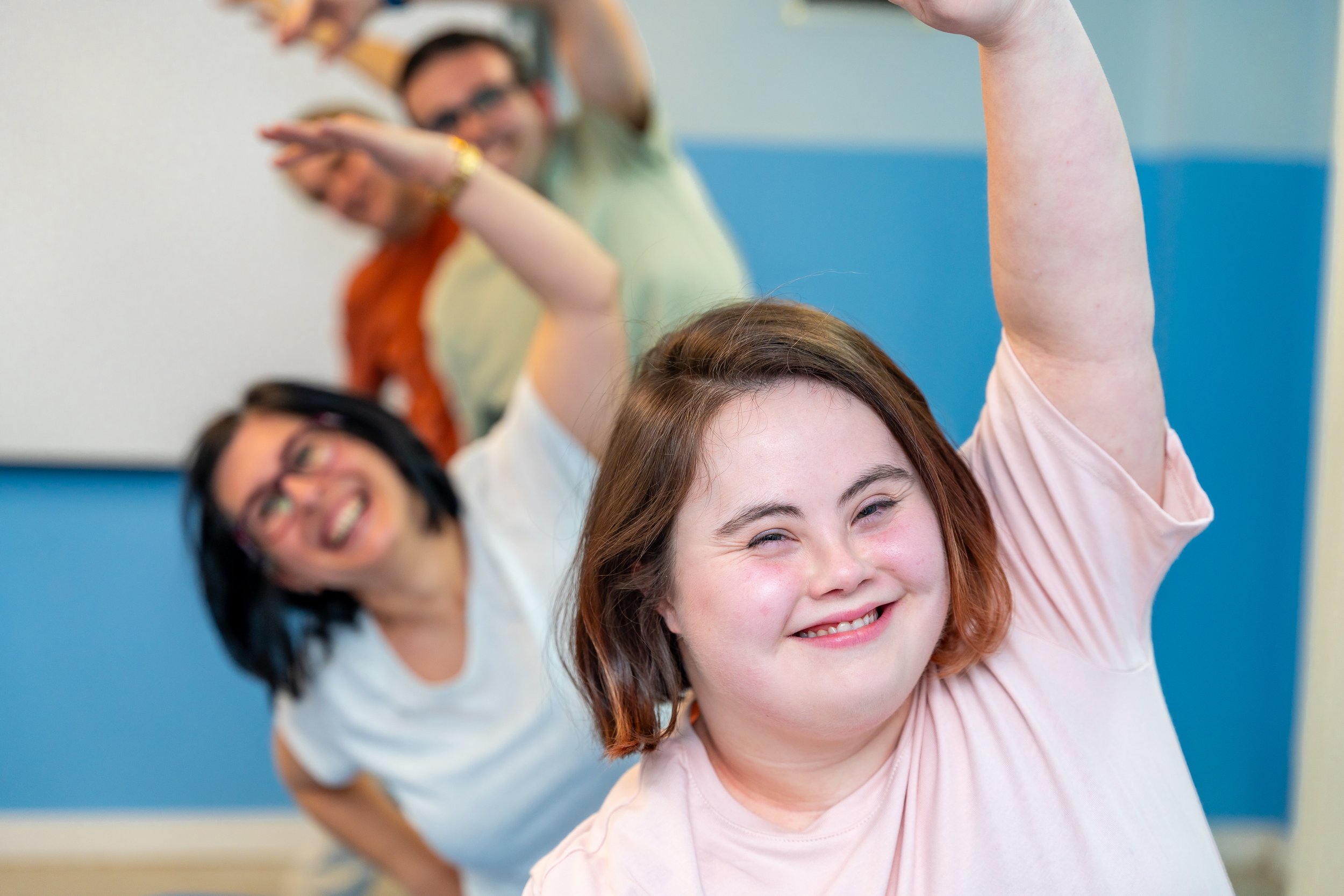 Multiple participants taking part in exercise class, stretching.