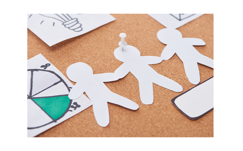 Corkboard with paper men cut out, next to pie chart