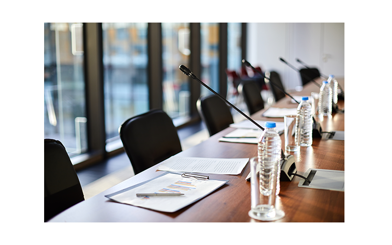 Zoomed in image of empty board room, with documents on table