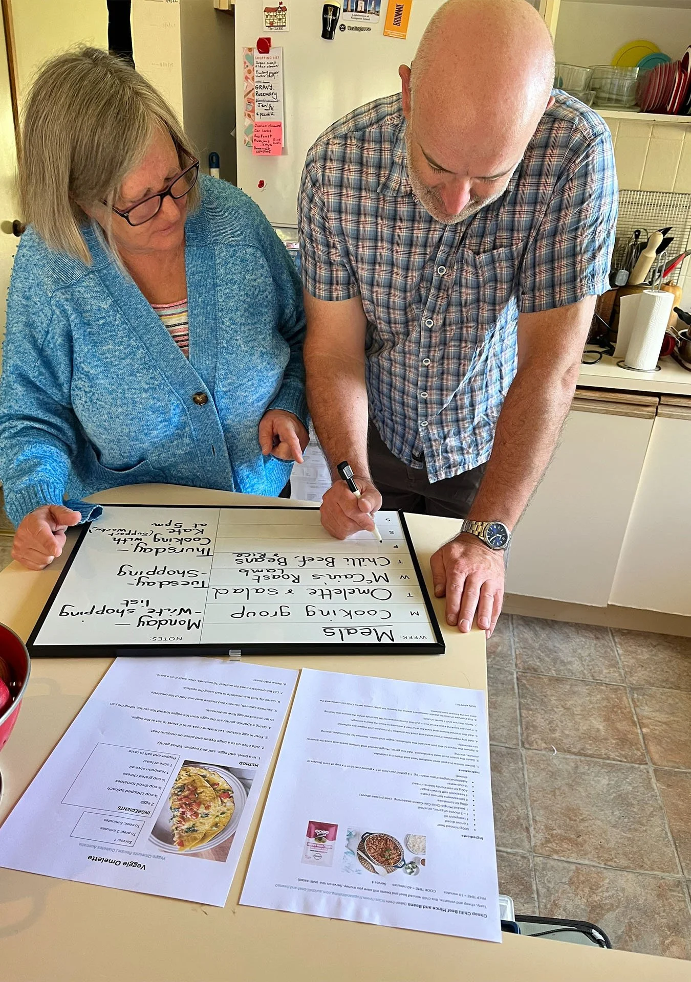 Jenny working alongside client to write down this week's meals on whiteboard