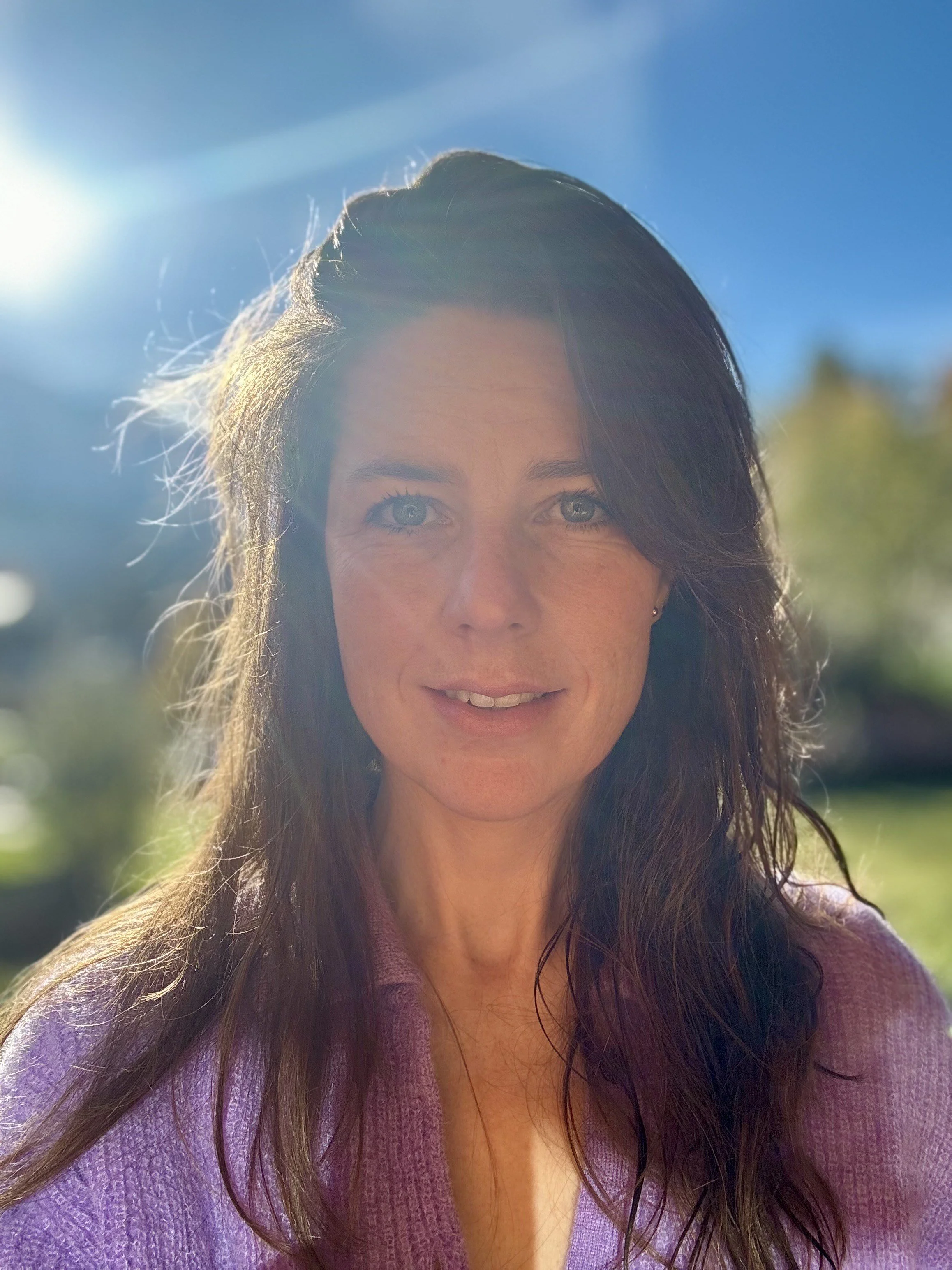 Femme en randonnée dans un paysage de montagnes, portant un manteau foncé et un sac à dos.
