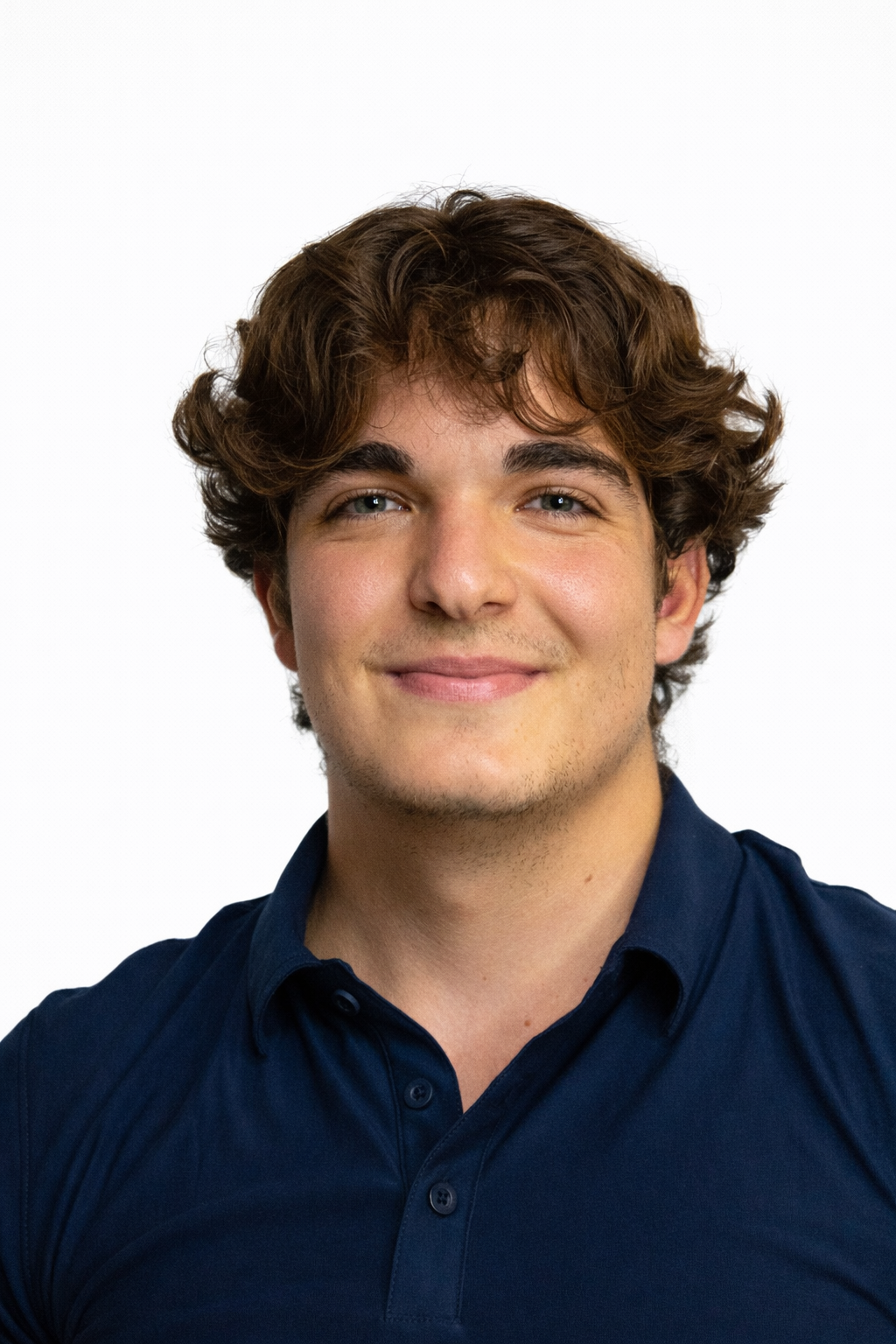 A young woman with curly hair smiling, wearing glasses, hoop earrings, and a striped shirt in an indoor setting.