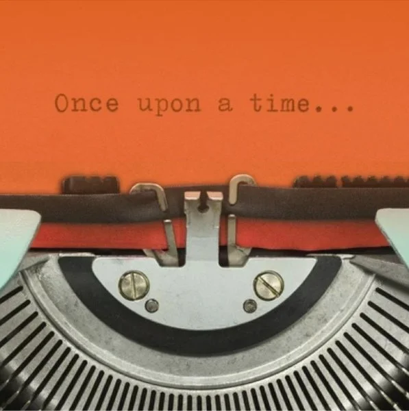Close-up of a vintage typewriter with an orange sheet inside, displaying the words 'Once upon a time...'
