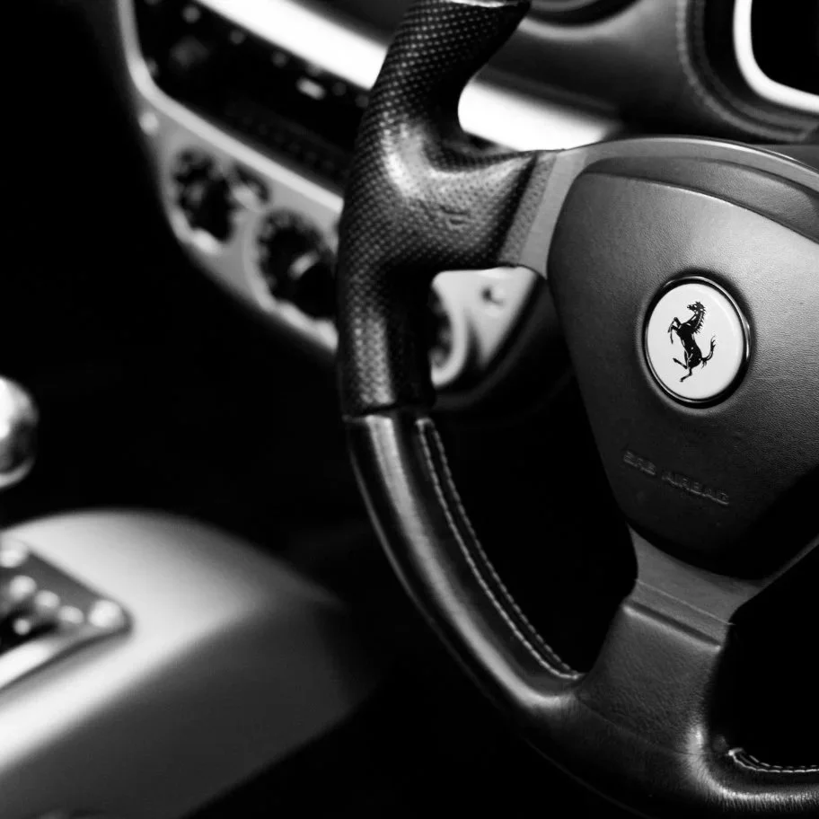 Close-up of a Ferrari steering wheel with the prancing horse logo.