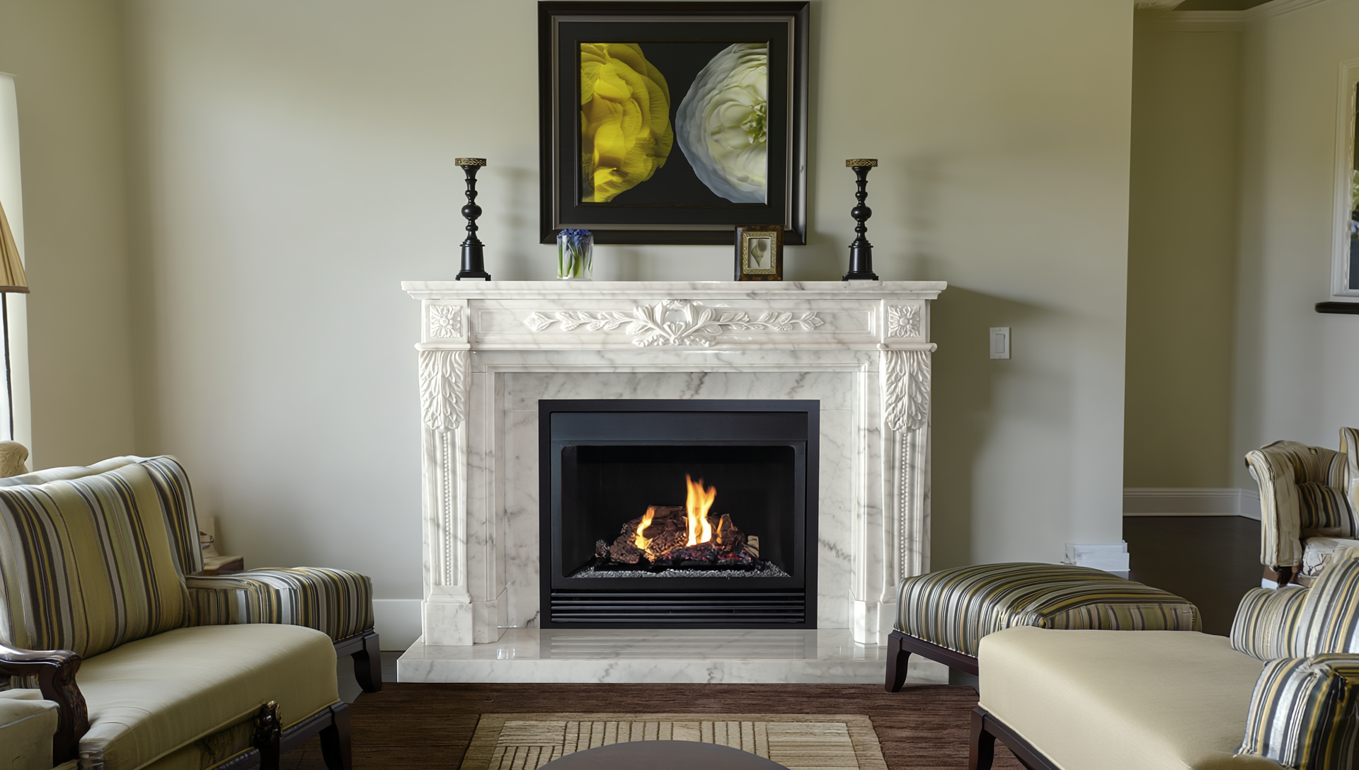 Living room with a white marble fireplace, a fire burning inside, and decorative items on the mantel. Above the fireplace hangs a large framed floral artwork.