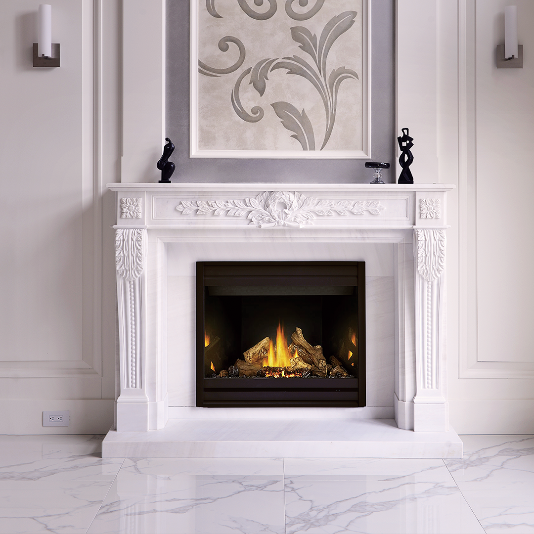 Elegant living room with a white ornate fireplace, lit with a gas fire and decorative black sculptures on the mantel. Above the fireplace is modern artwork with swirling floral patterns, flanked by two sconces on white walls with marble flooring.