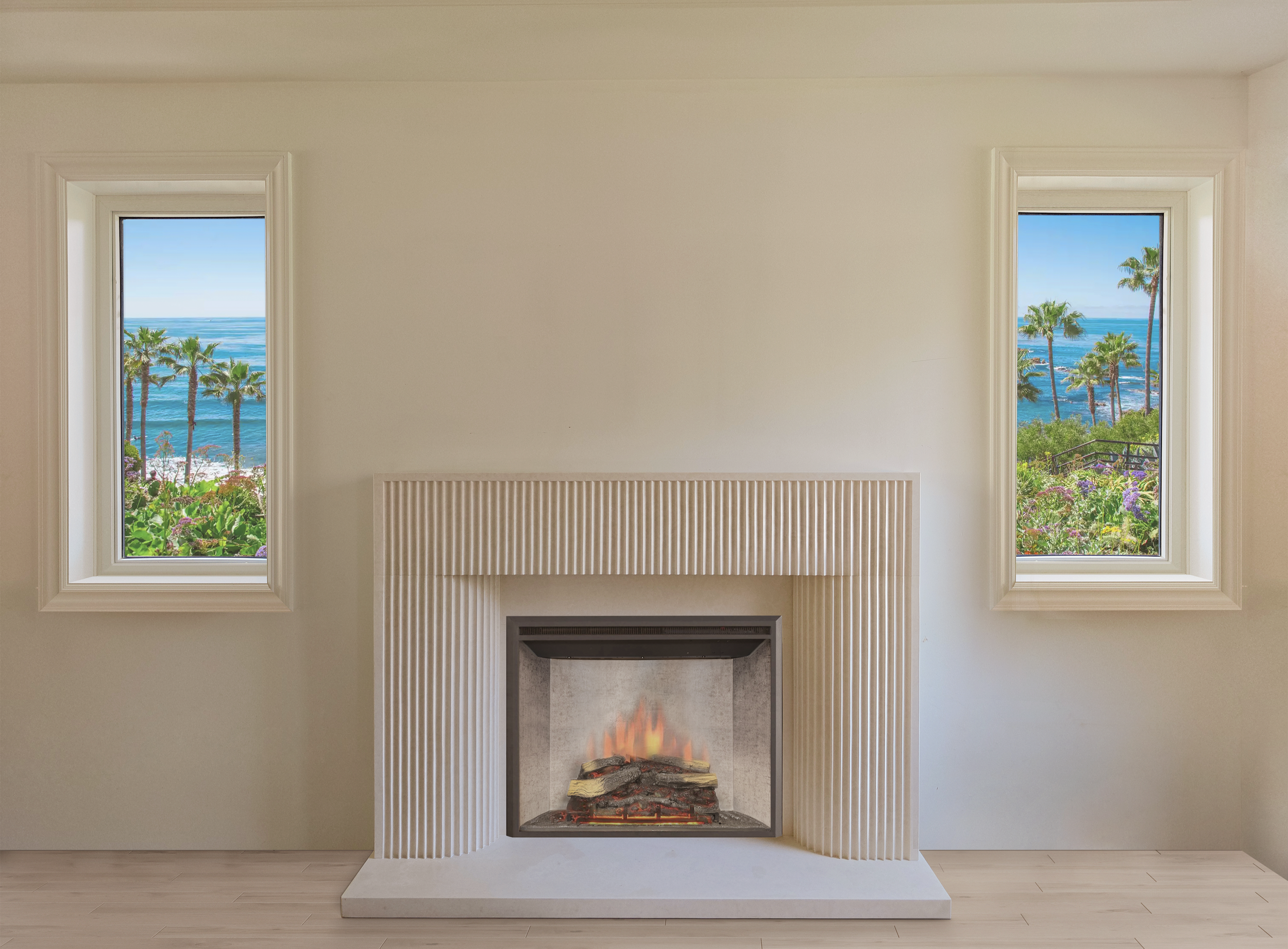 Living room with white fireplace, tall windows showing ocean and palm trees, and light wood floors.