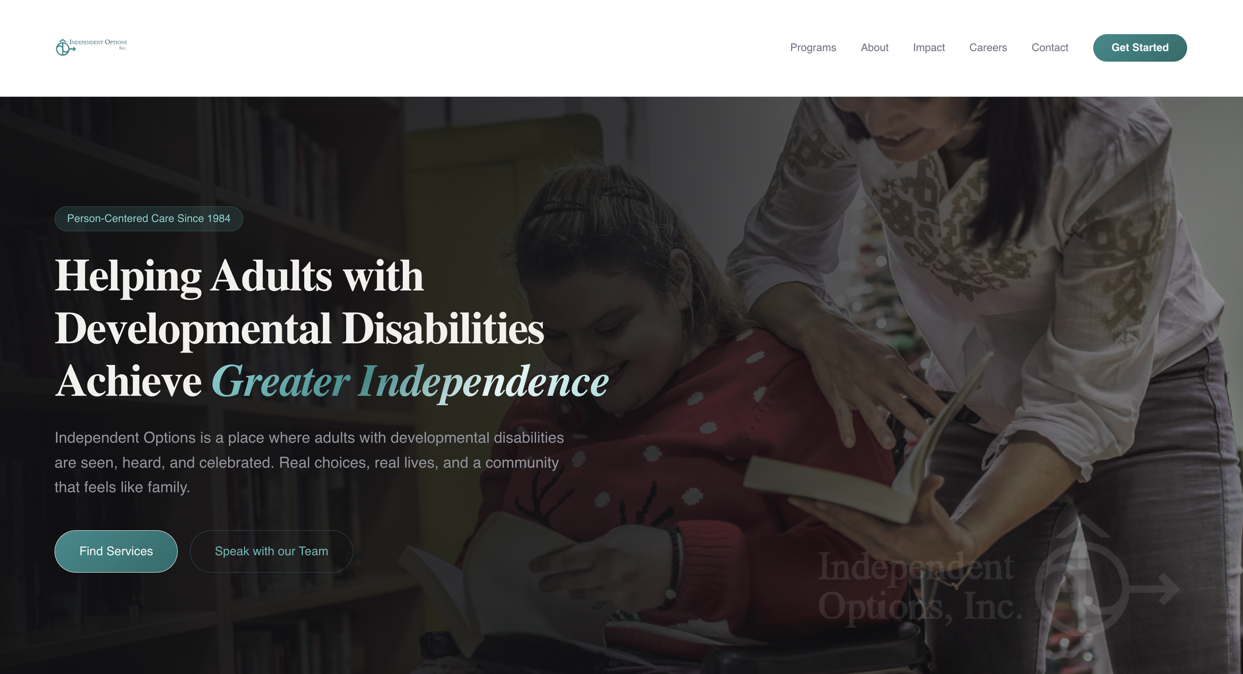 A caregiver and a young girl sharing a moment in a library, with bookshelves in the background.