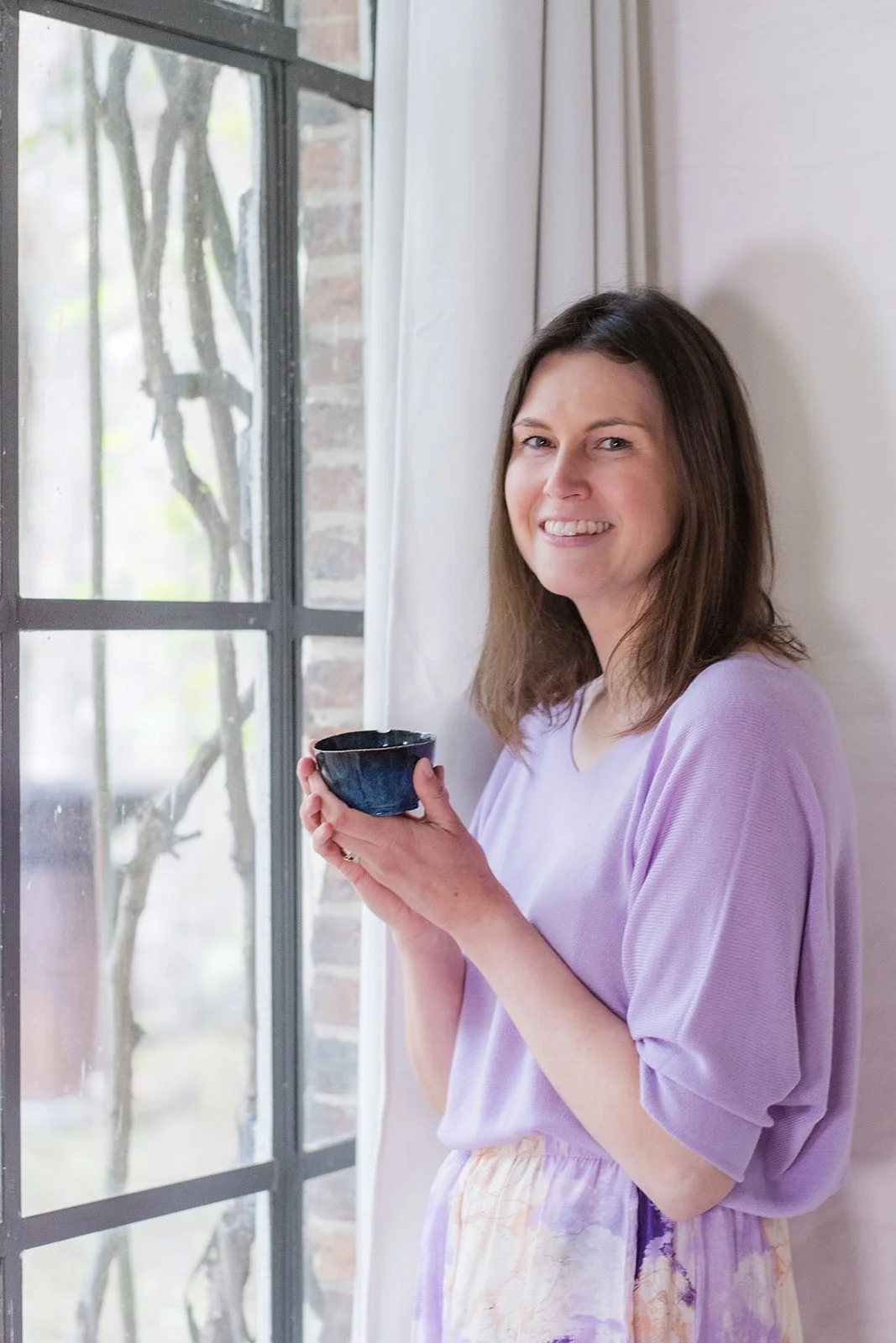 Vrouw met een kopje in haar handen, die strategisch advies en ondersteuning biedt aan ondernemers.