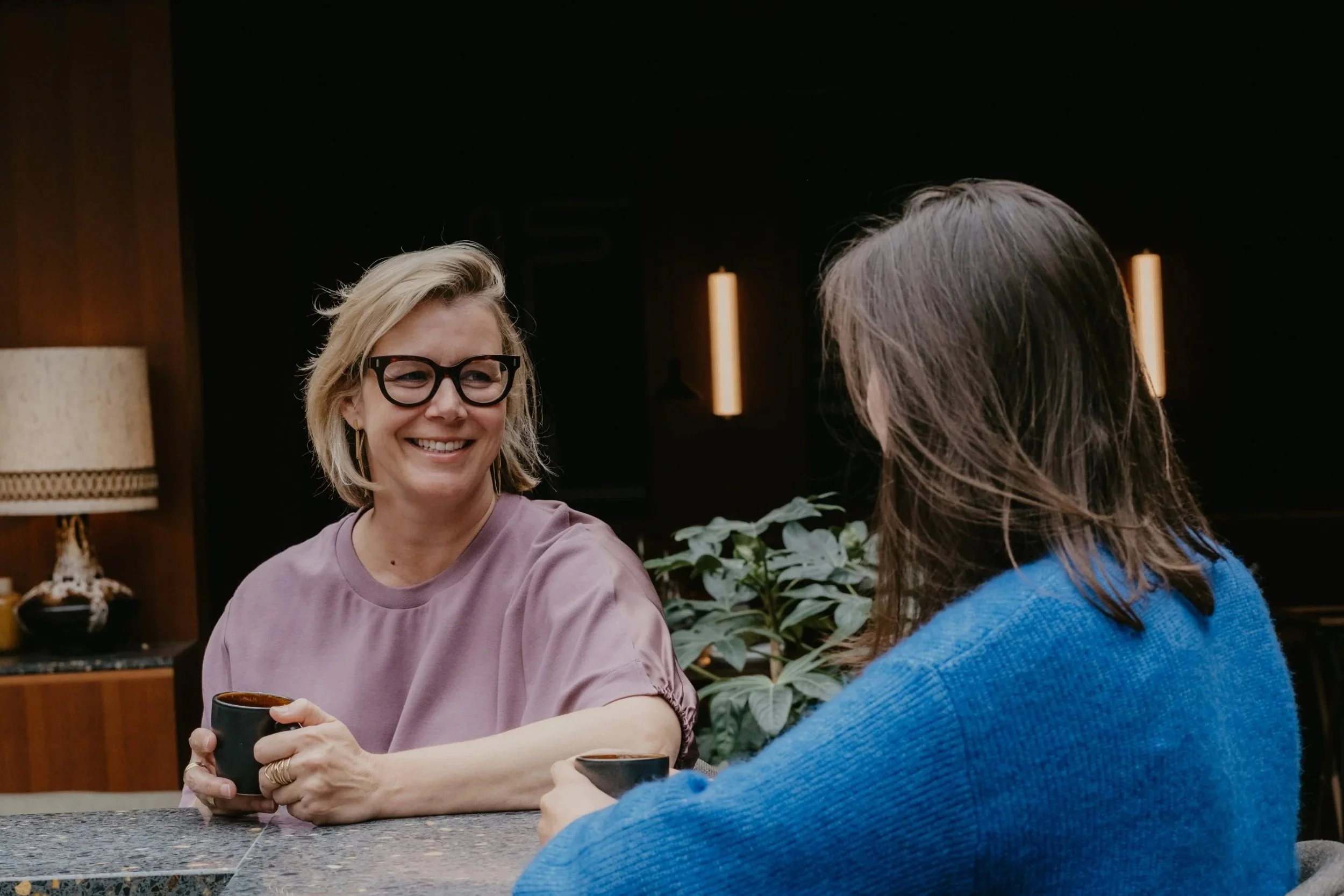 Twee vrouwen in een gezellig café, pratend en lachend.
