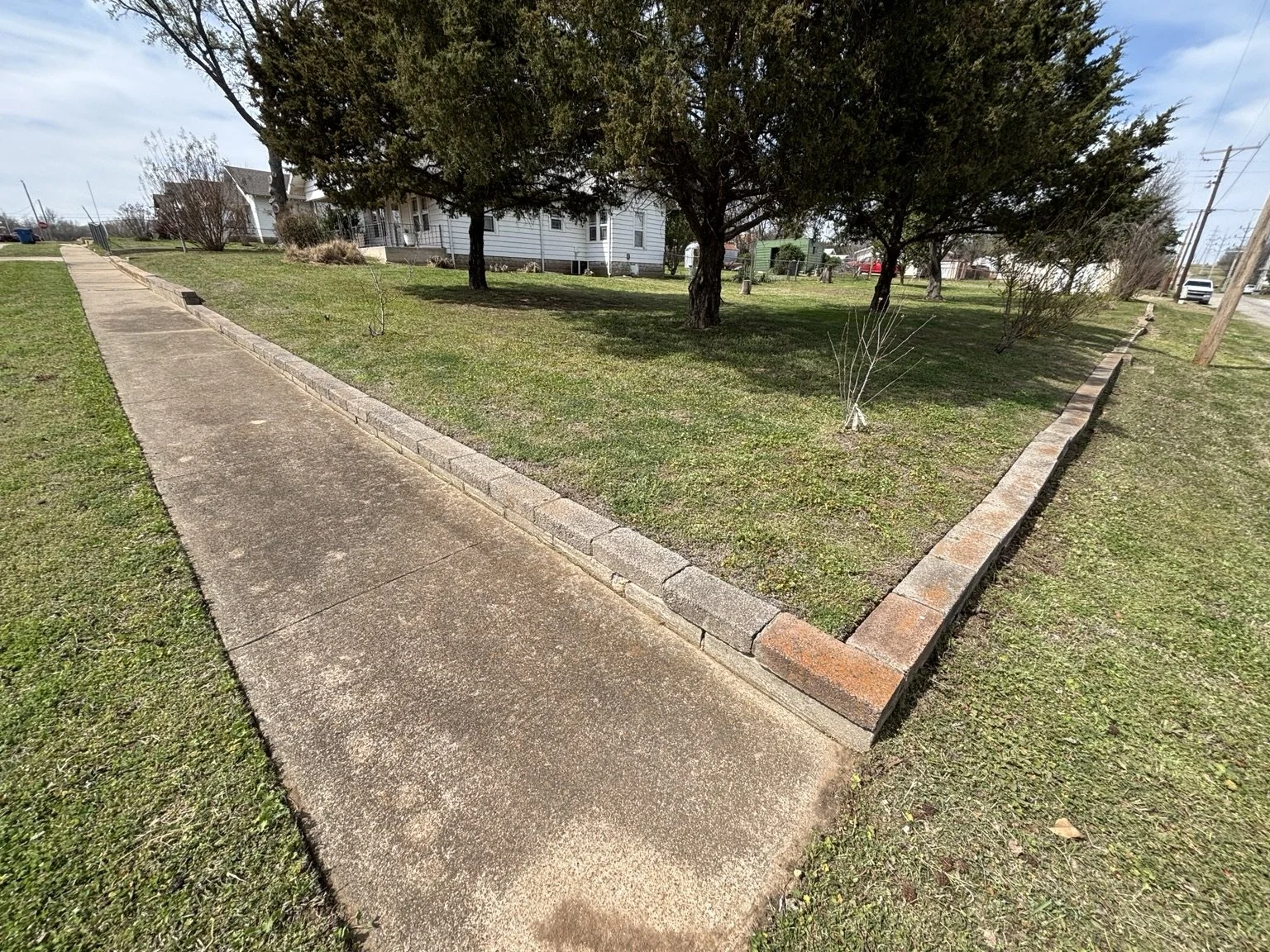 Bi-weekly lawn maintenance in Drumright, Oklahoma, with clean edging along sidewalks and detailed trimming for a well-maintained residential property.