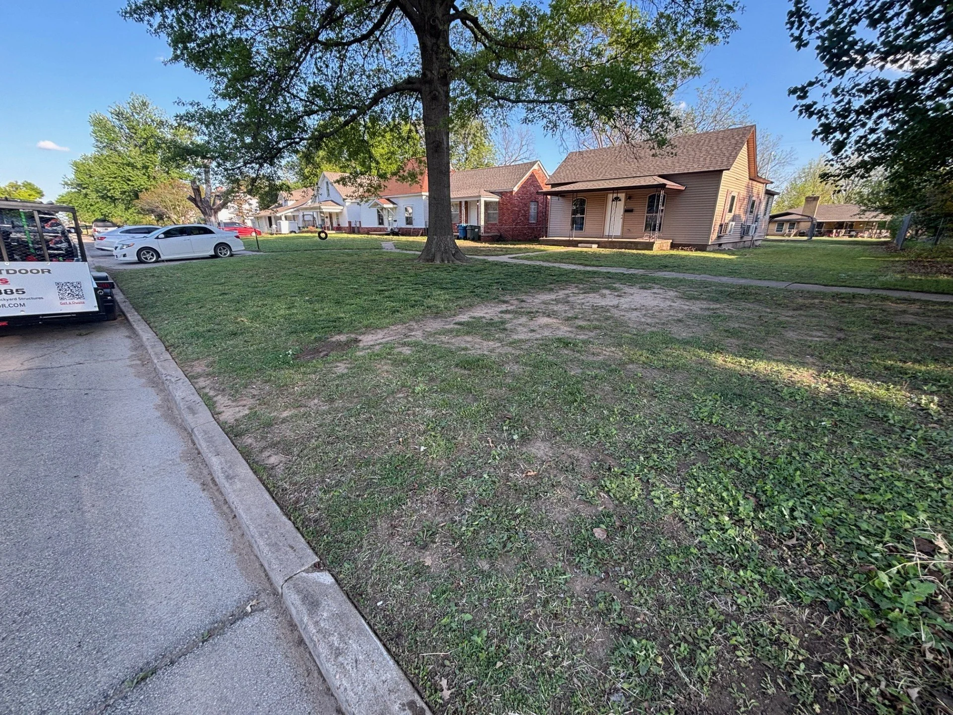 Lawn maintained under challenging conditions with weeds and thin turf — consistent service helps improve overall appearance over time.