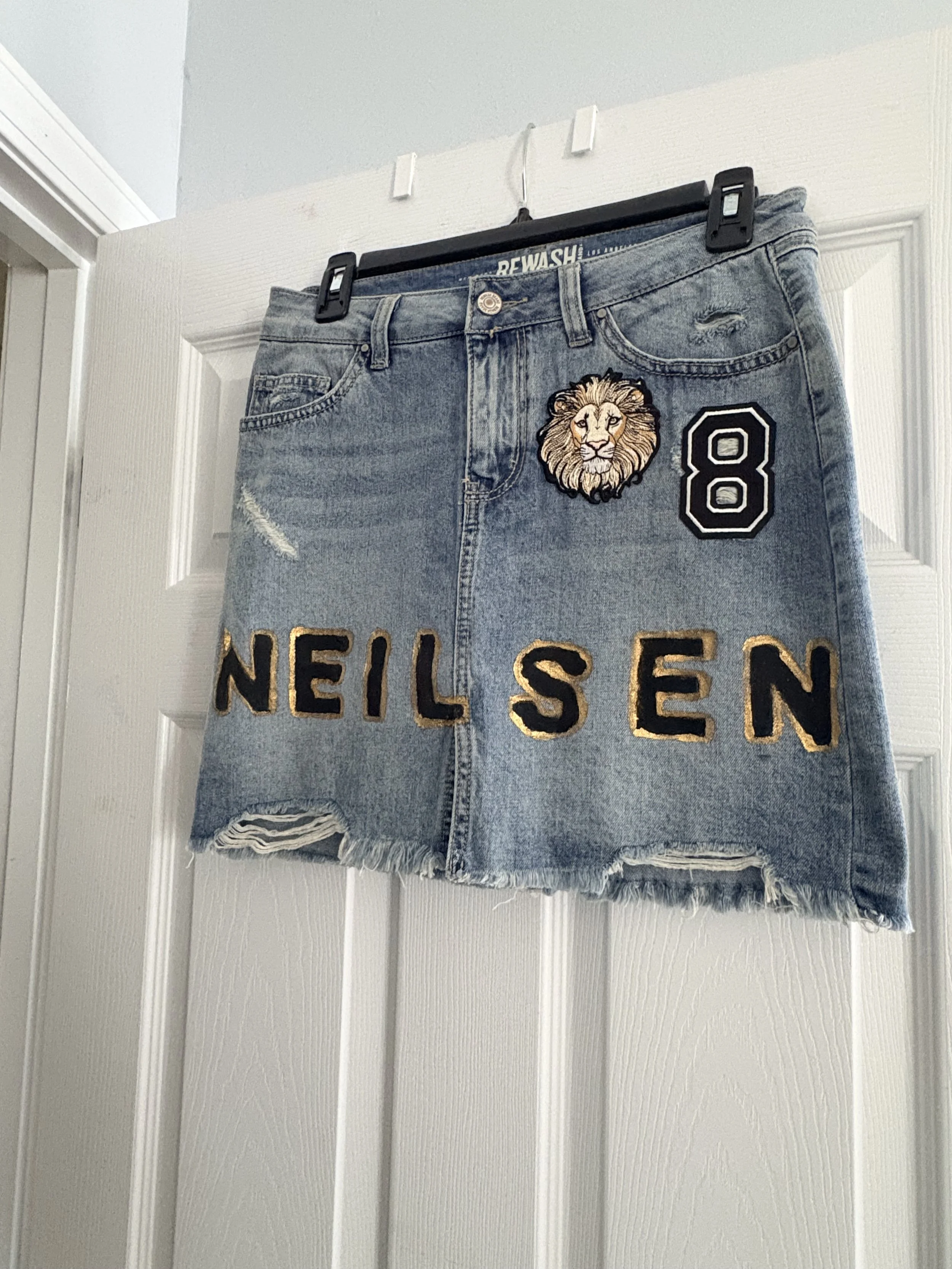 Medium wash denim skirt with last name hand painted. Logo and jersey number patched on.