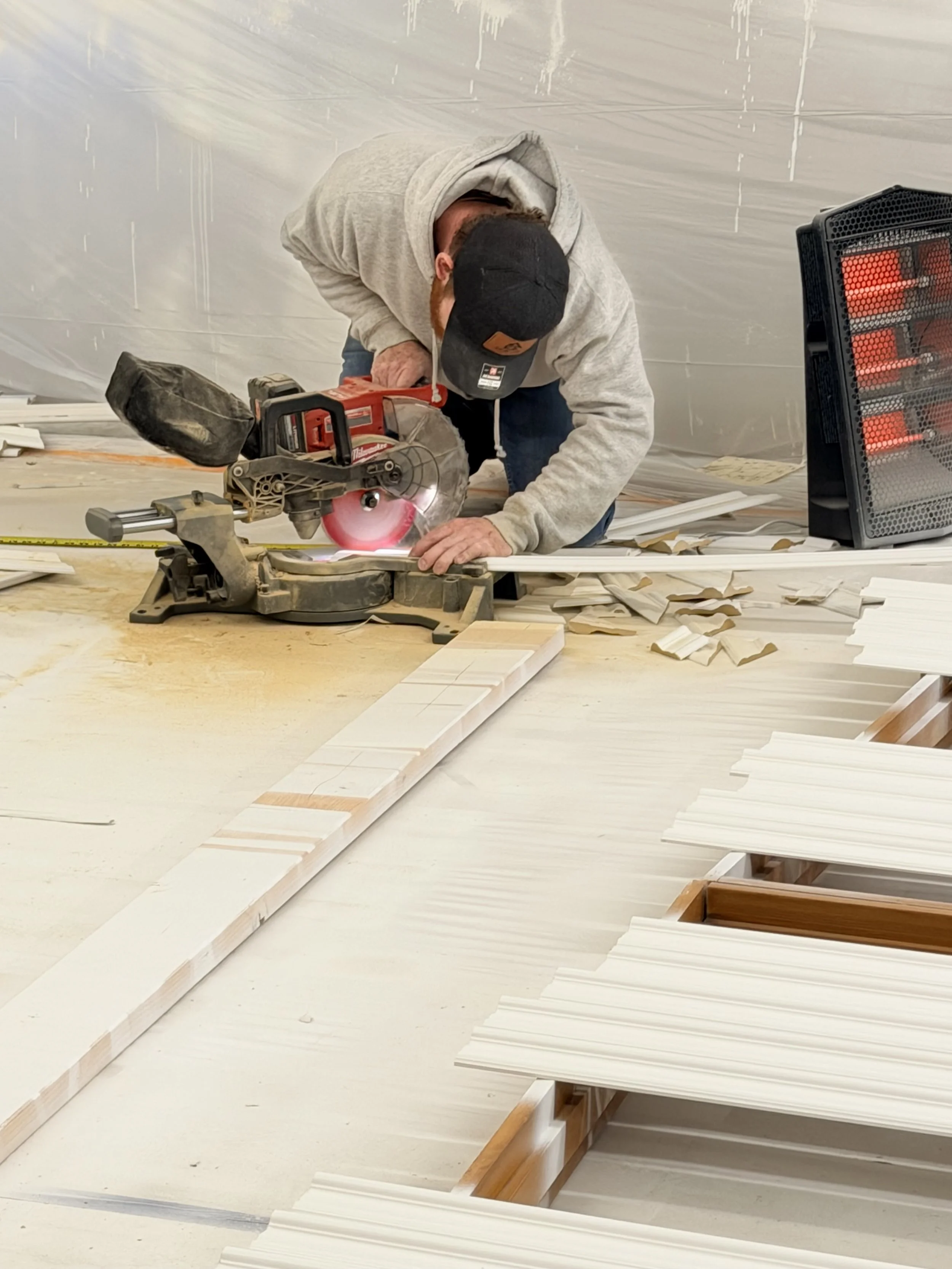 Person using a miter saw to cut a piece of wood in a workshop.