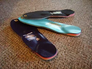 Three insoles placed on a carpeted floor.