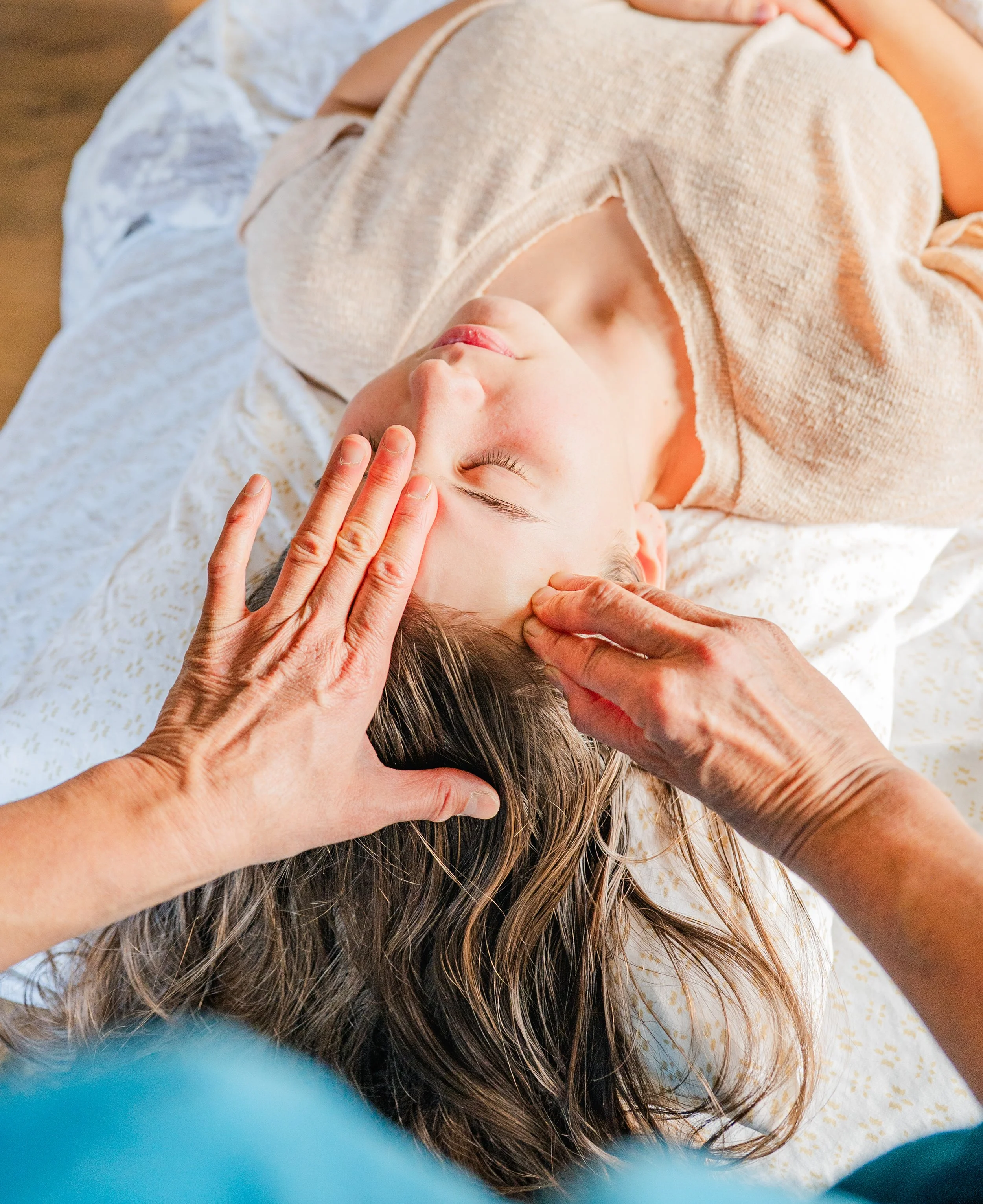 Person receiving a cranial massage from a practitioner.