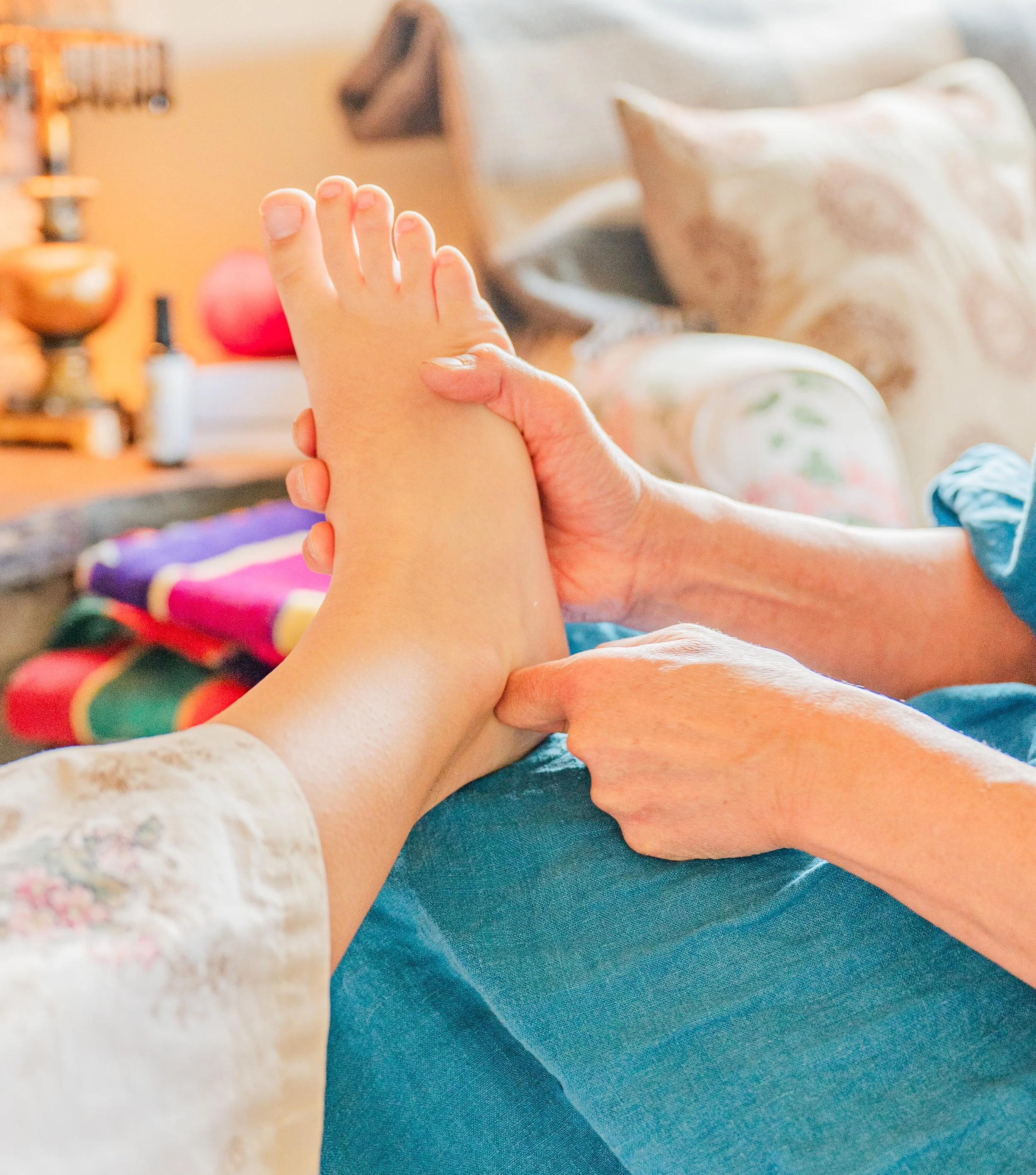 Person receiving a foot massage from another person in a cozy, well-lit room.