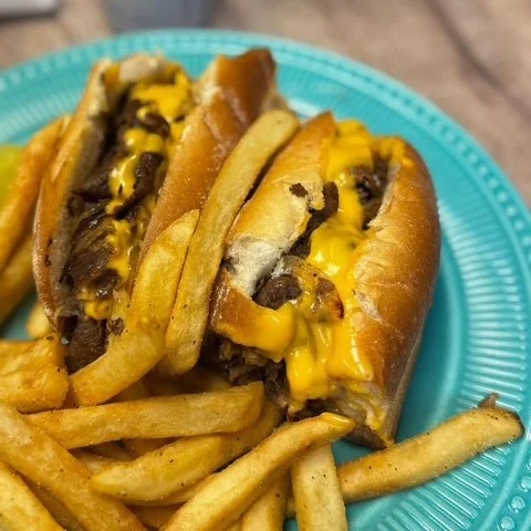 Two cheeseburgers with French fries on a blue plate.