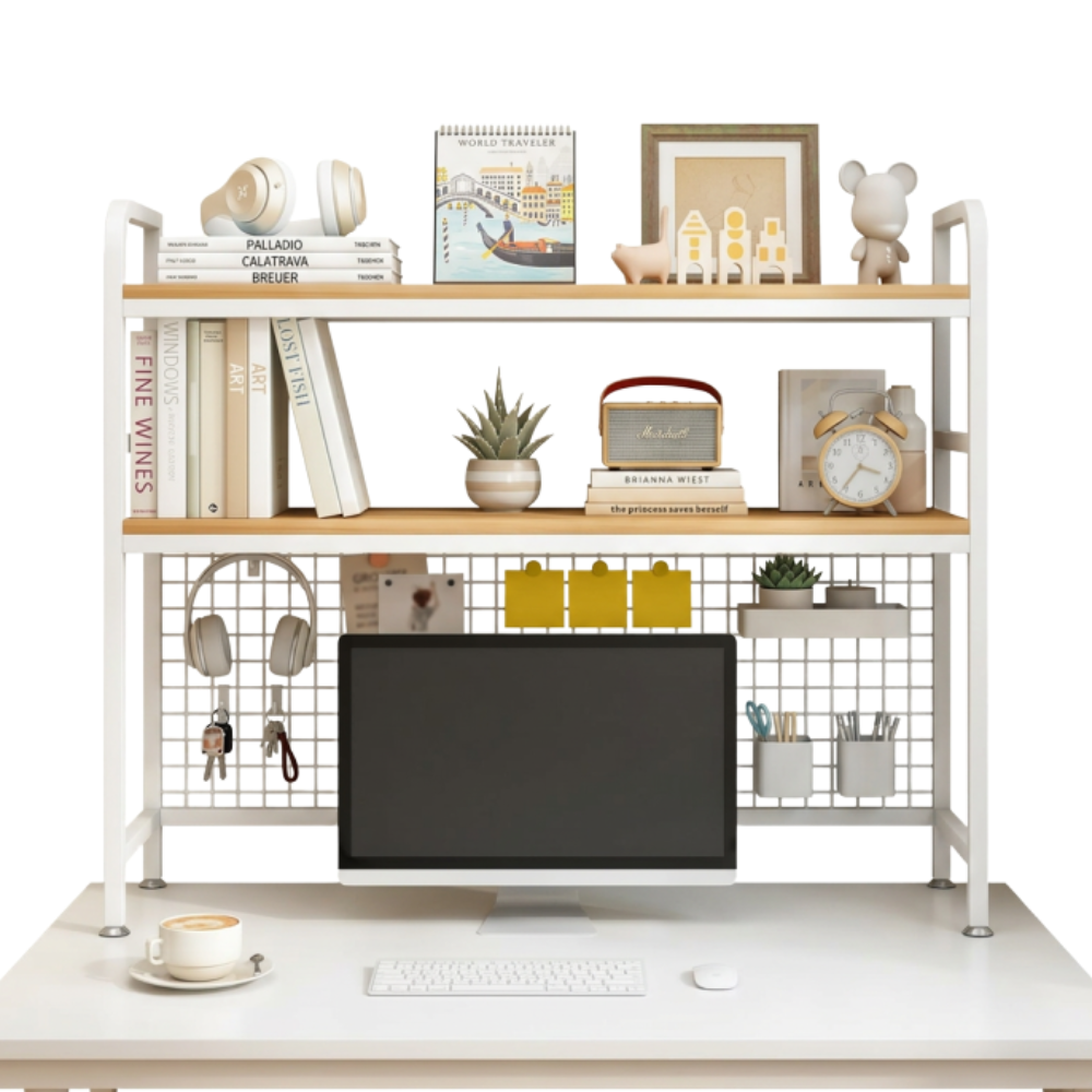 A modern white desk with a computer monitor, keyboard, and mouse, and a coffee cup on a saucer. Behind the monitor is a white grid with small decorative items, including headphones, keychains, and pens. Above the desk are pulled wooden shelves with books, a potted plant, a vintage alarm clock, a framed picture, small animal figurines, and a calendar.
