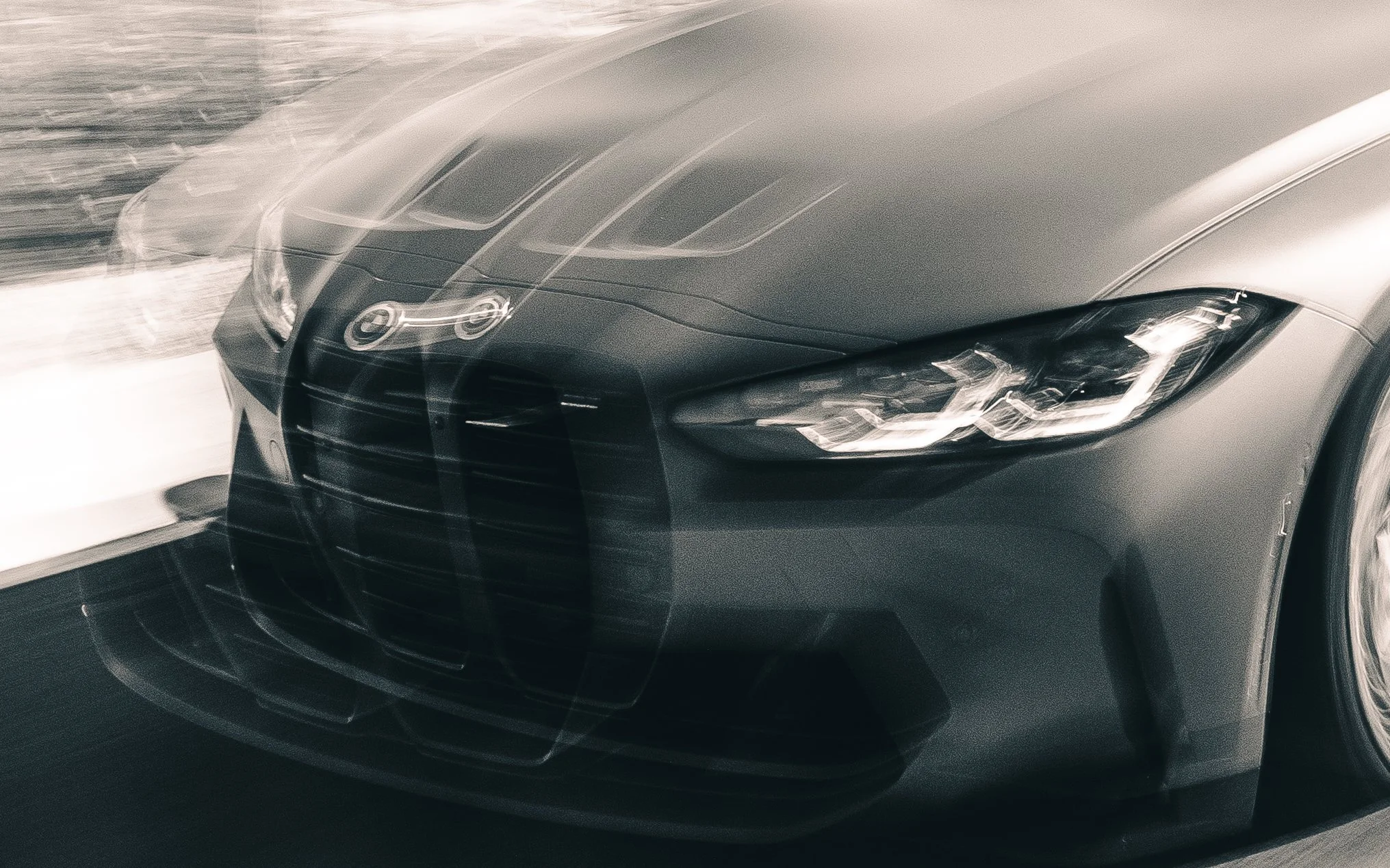 Close-up of a luxury car's front end with sleek headlights and a metallic gray finish, parked on a snowy surface.