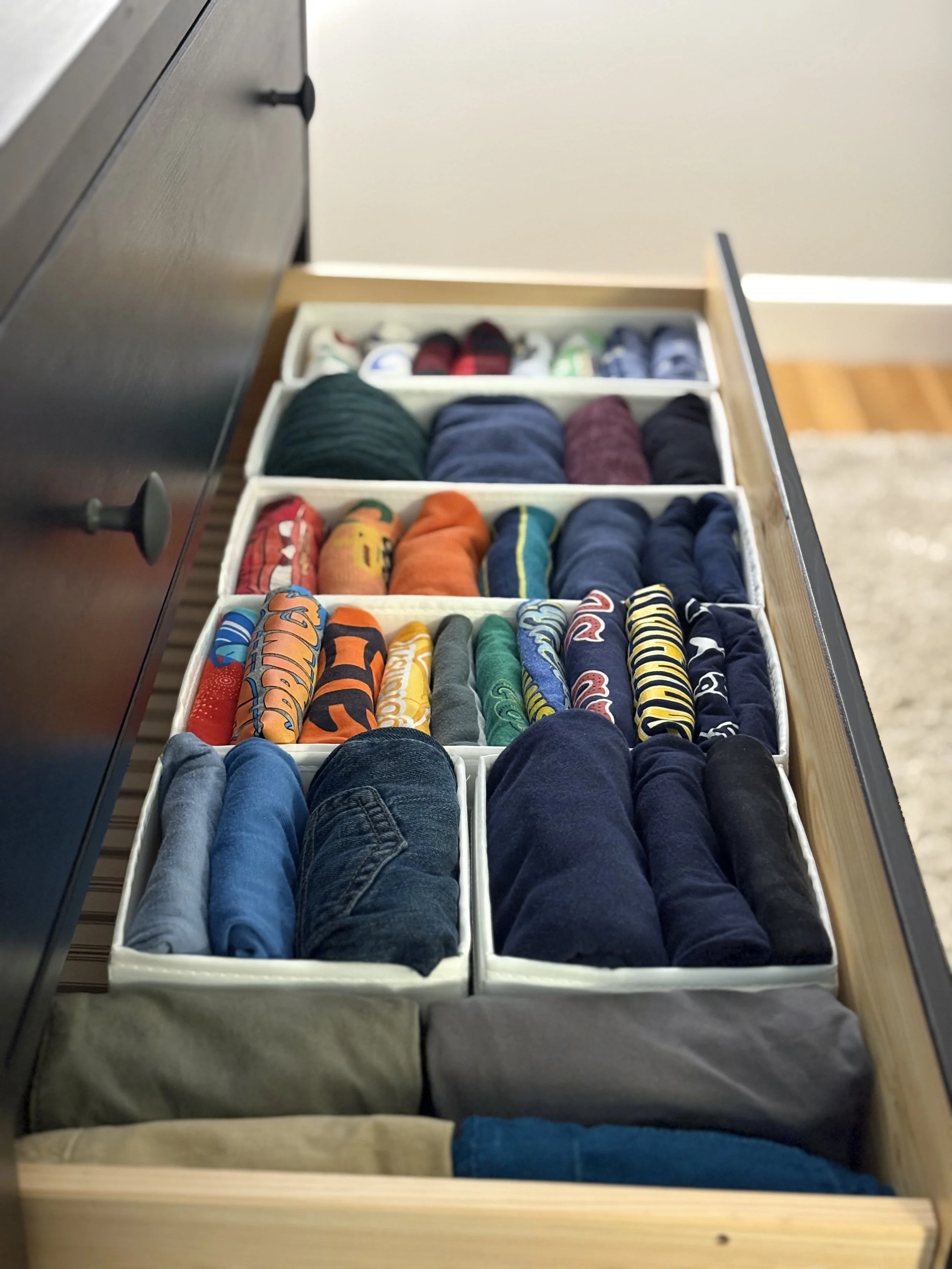 Open drawer with neatly folded clothing, organized in compartments.