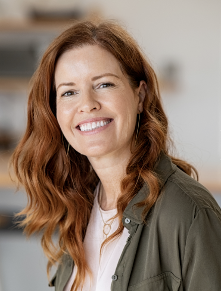 A woman with long, wavy red hair smiling in a casual setting.