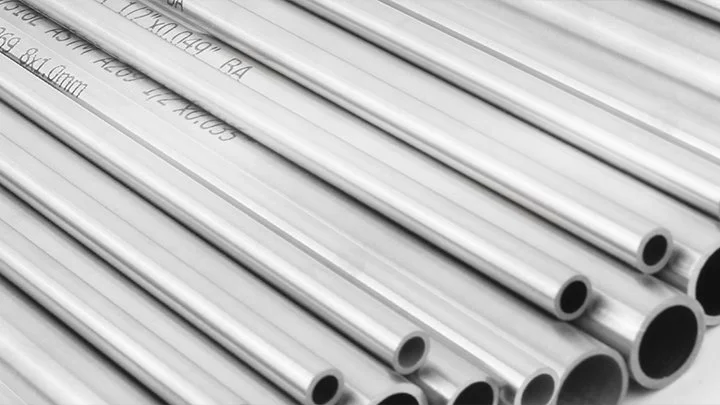 A close-up of multiple metal pipes arranged parallel, with handwritten markings on some pipes.