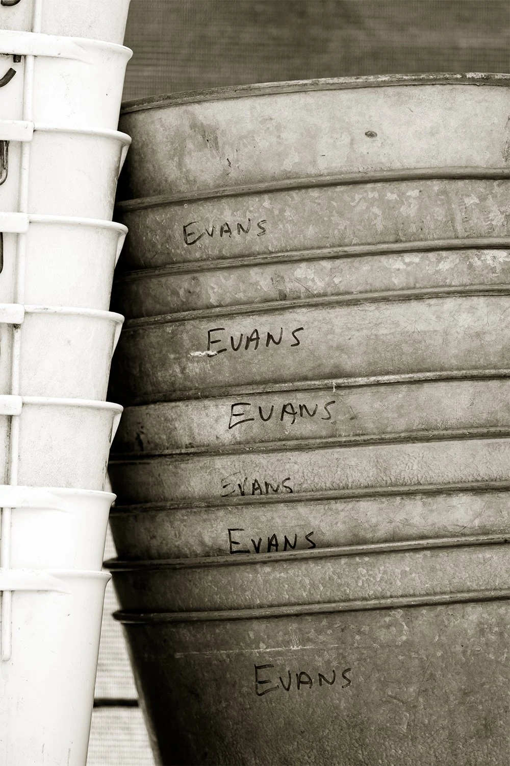 Stacked metal buckets with the name 'Evans' handwritten on each one.