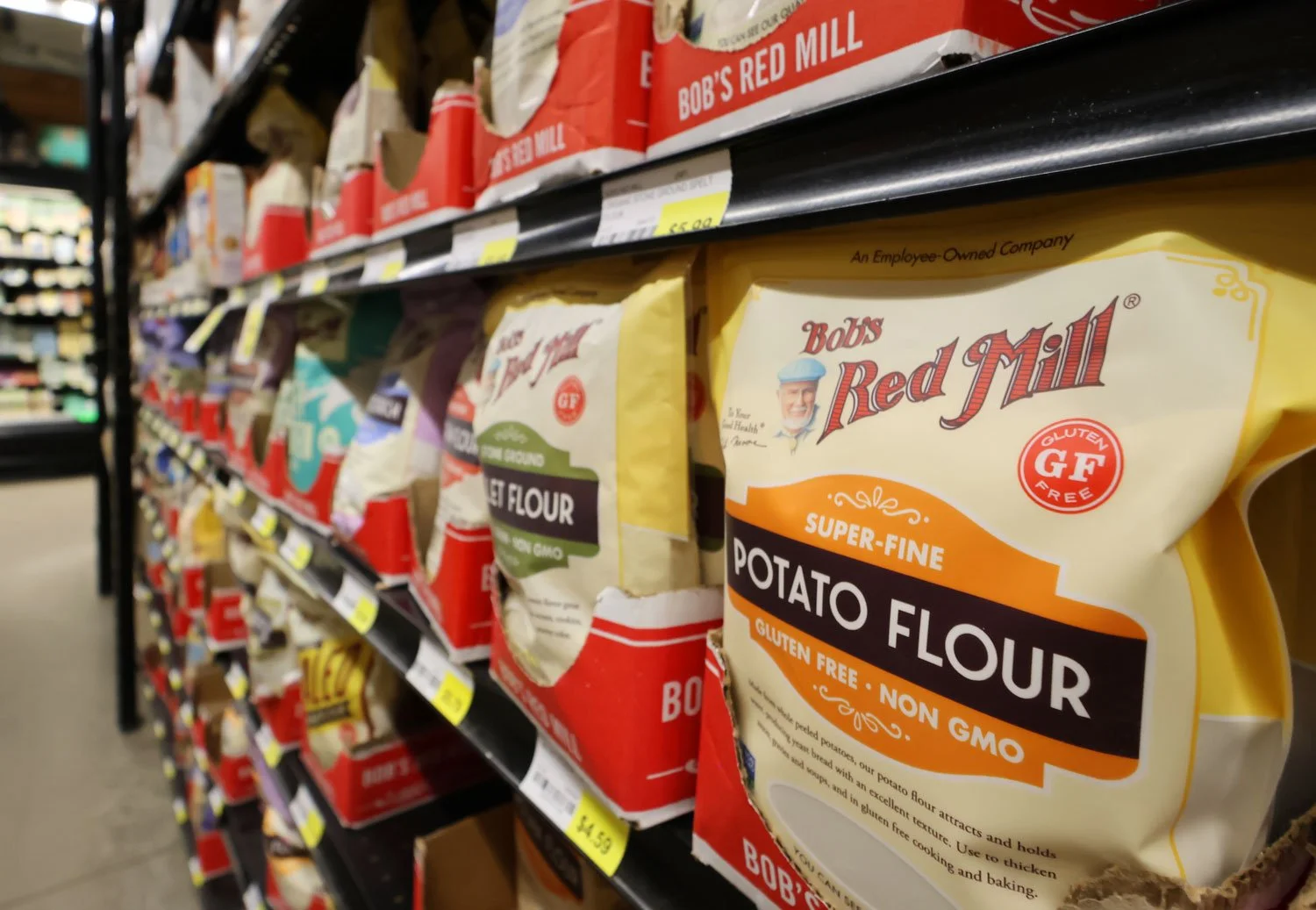 Shelf of Bob's Red Mill products, including gluten-free potato flour bags in store aisle.