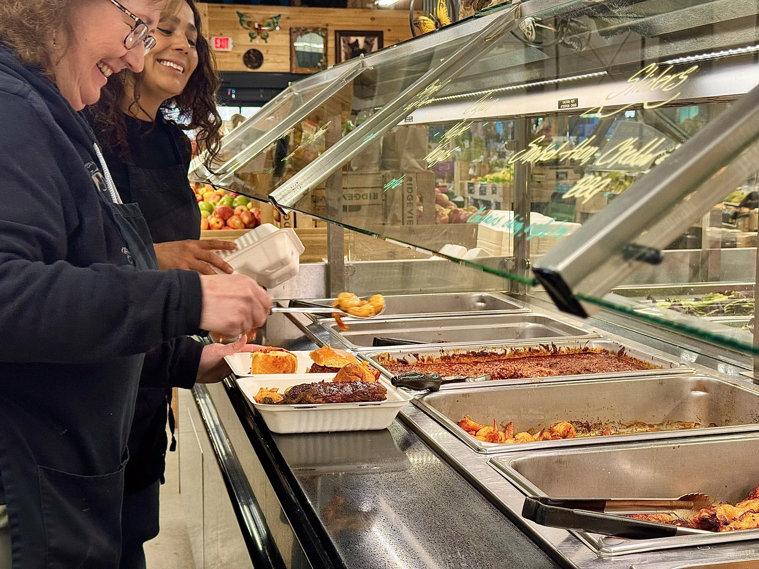 Merrill's hot food bar with smiling customers scooping food.
