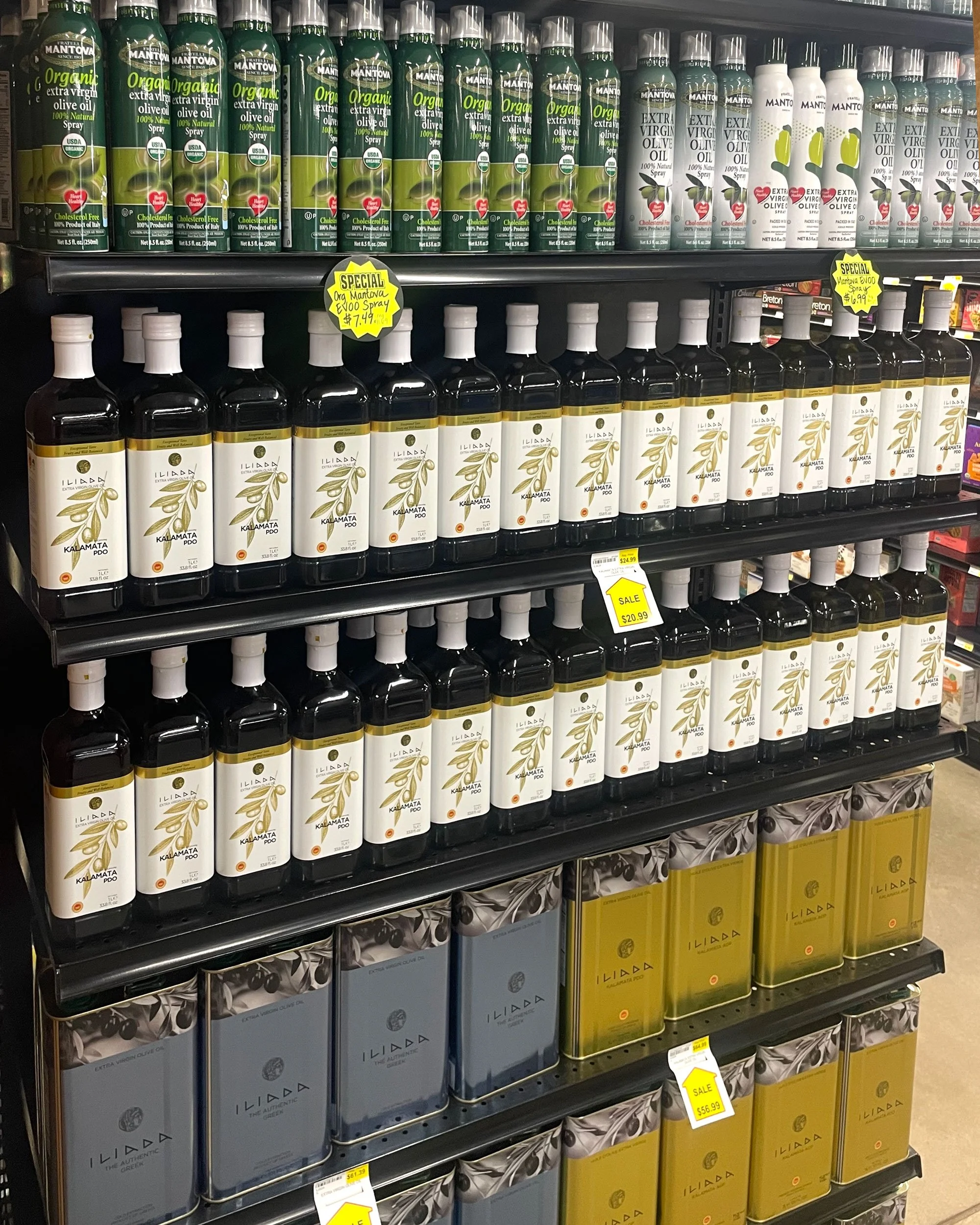Olive oil in spray bottles, glass bottles and canisters on shelf.