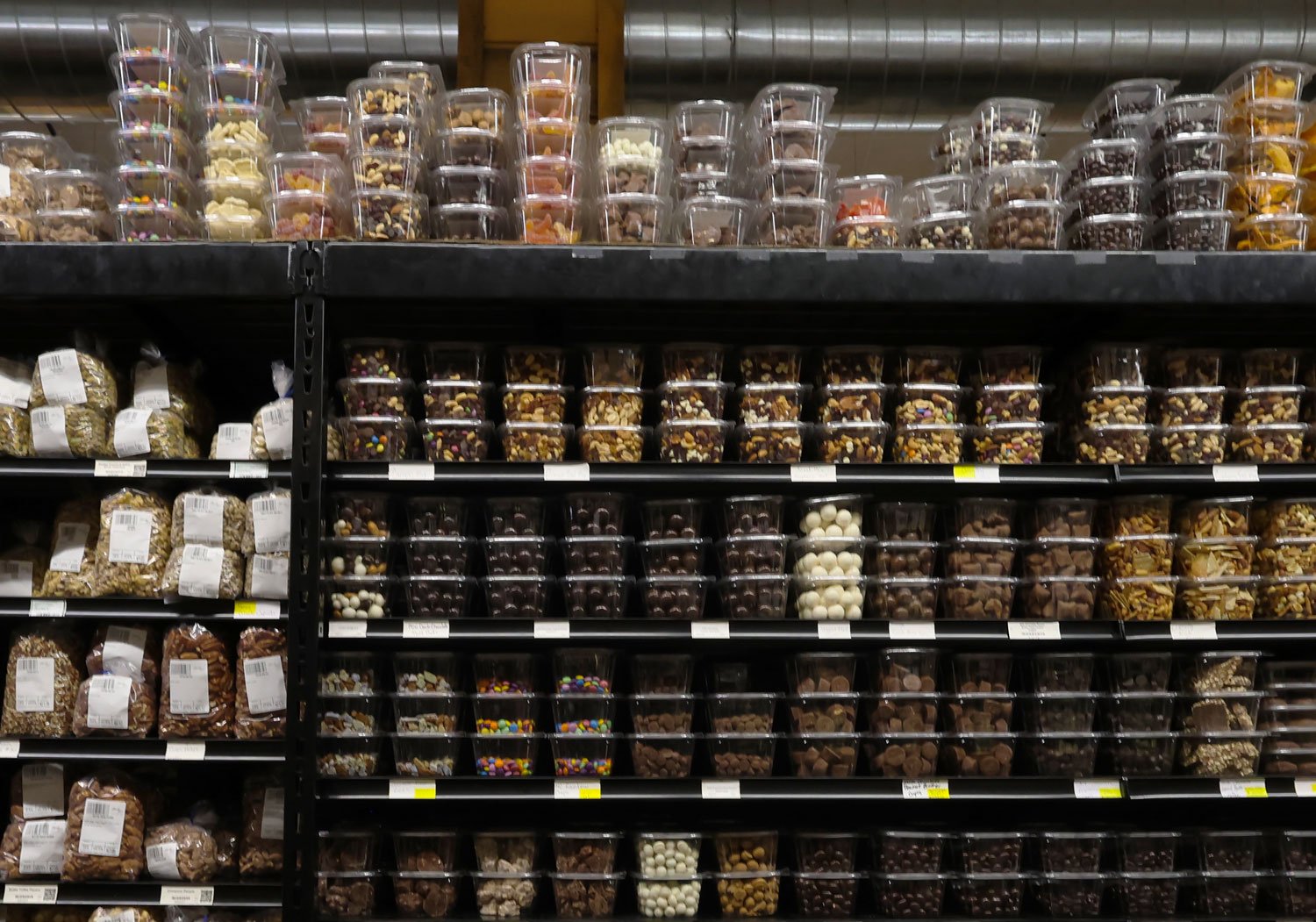 Store shelf stocked with various types of chocolates and candies in plastic containers.