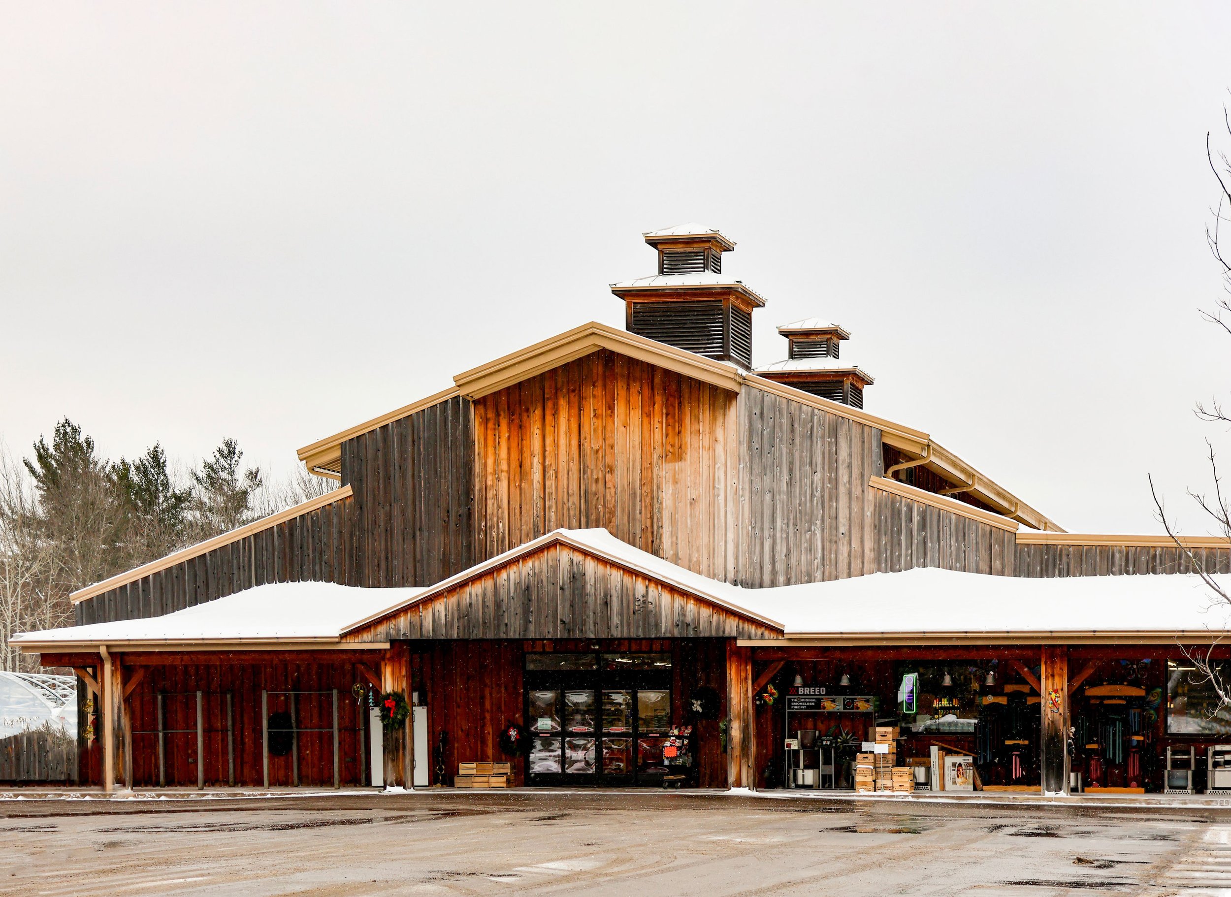 A rustic wooden building with a snow-covered roof and three small towers on top, set in a winter landscape.