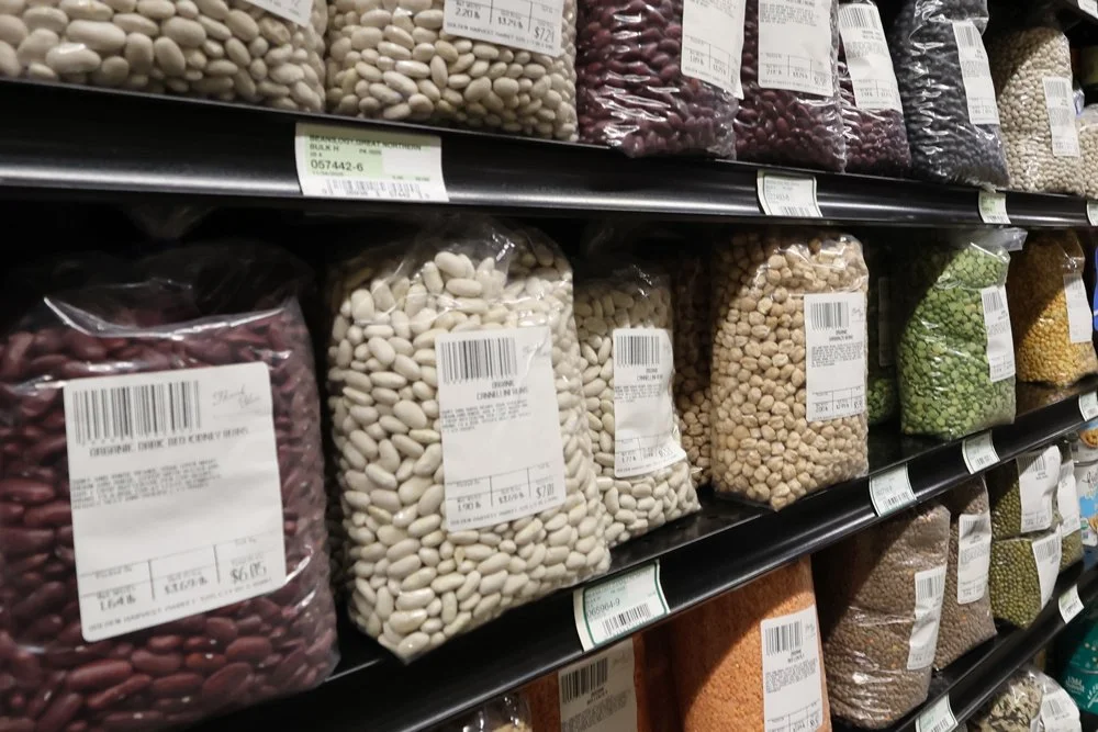 Multiple bags of assorted dried beans on store shelves.