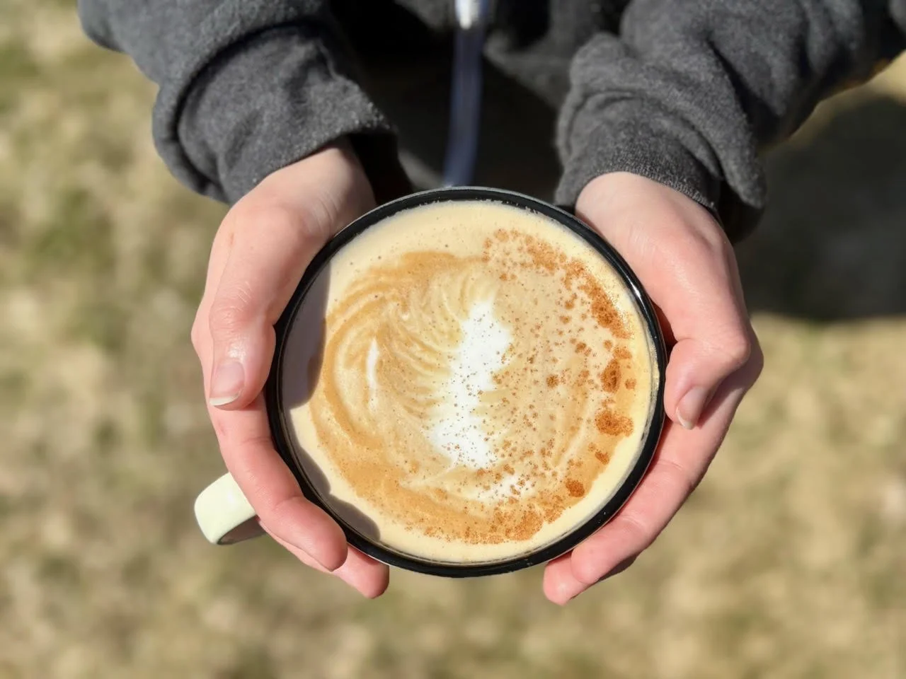 Fresh brewed coffee in a mug being held in someones hands.