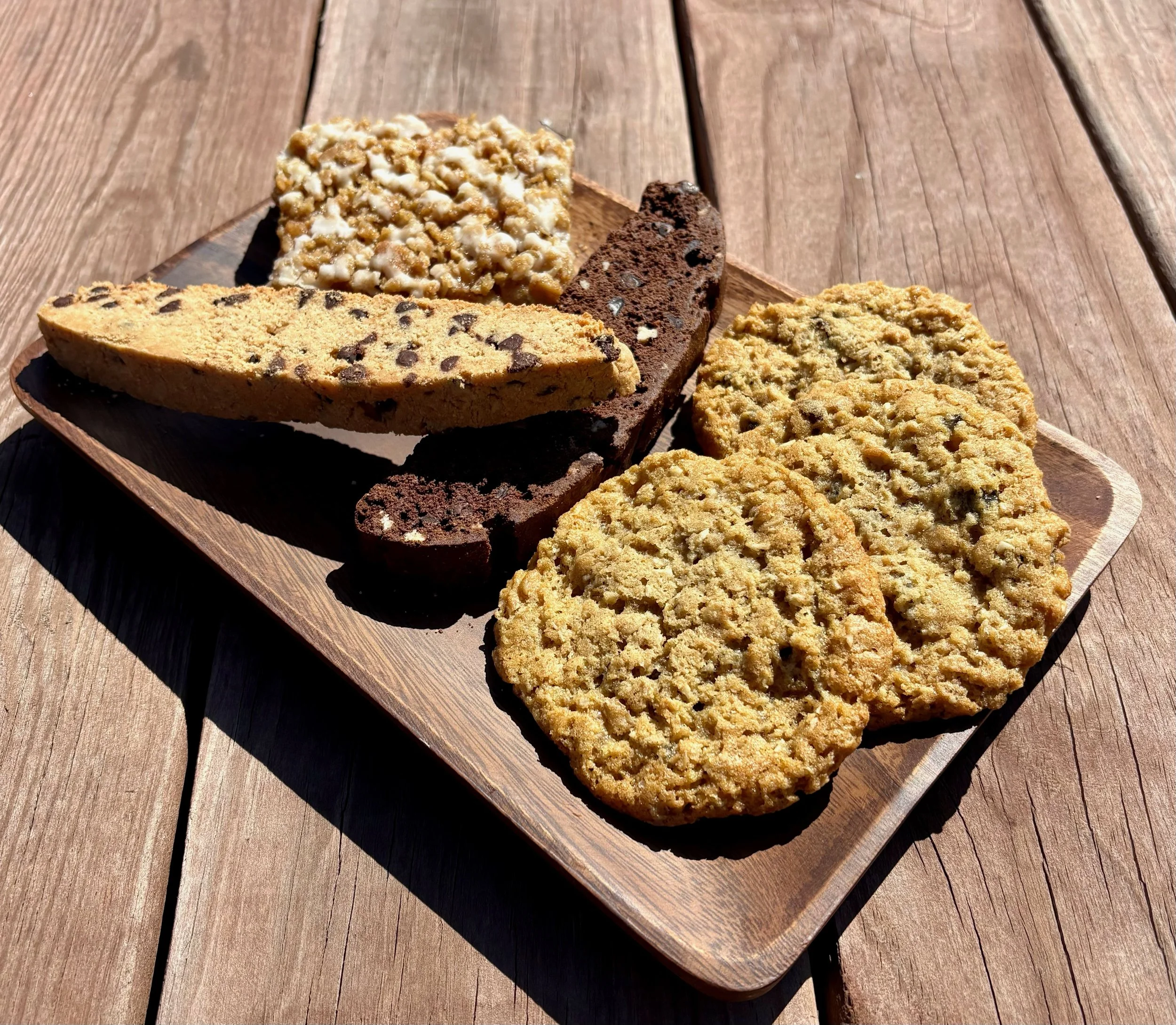 Freshly baked cookies, biscotti and a bar on a wooden platter.