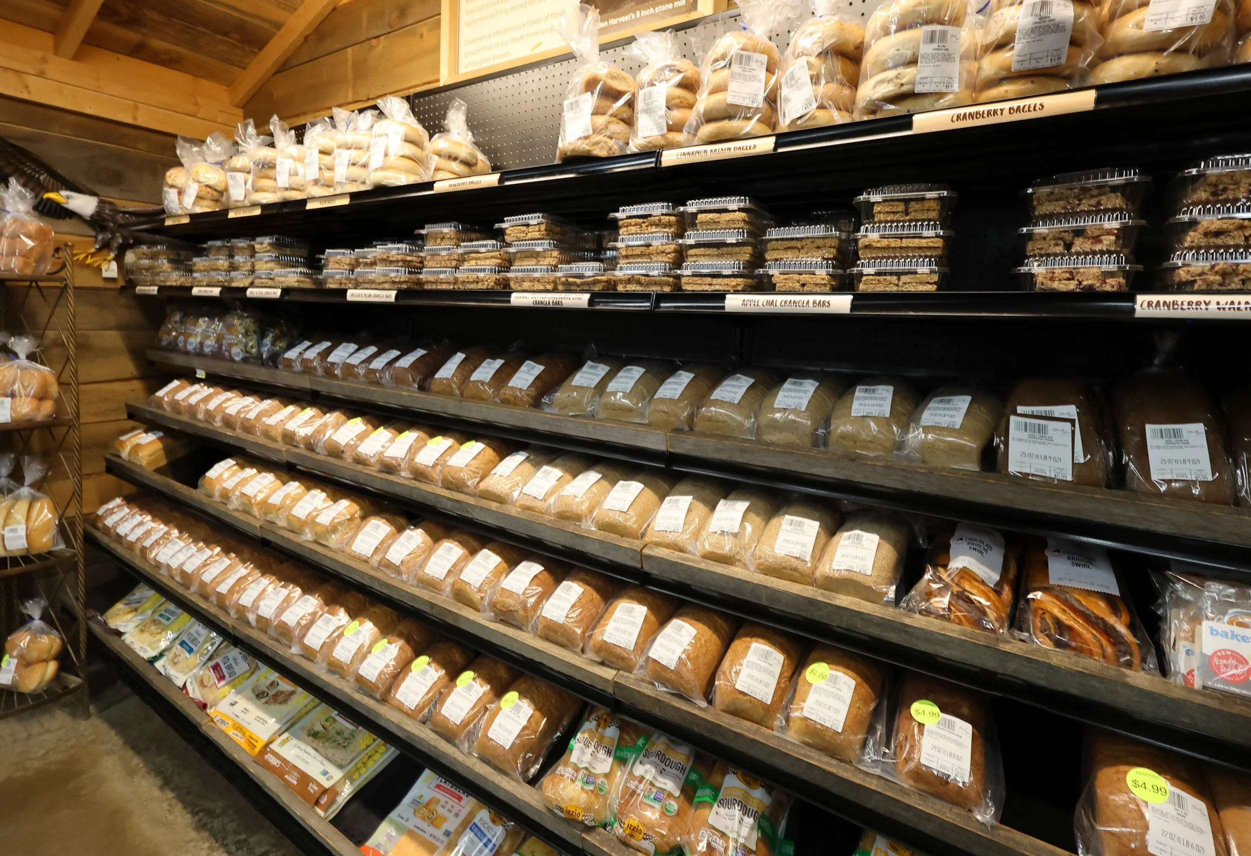 Shelves stocked with various types of bread and baked goods in a bakery section of a store.