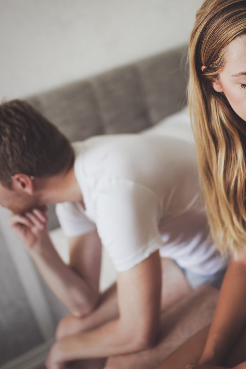 couple sitting on the bed being sad