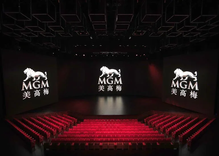 Empty theater with red seats and large screens displaying the MGM logo, a silver lion, in Chinese characters.