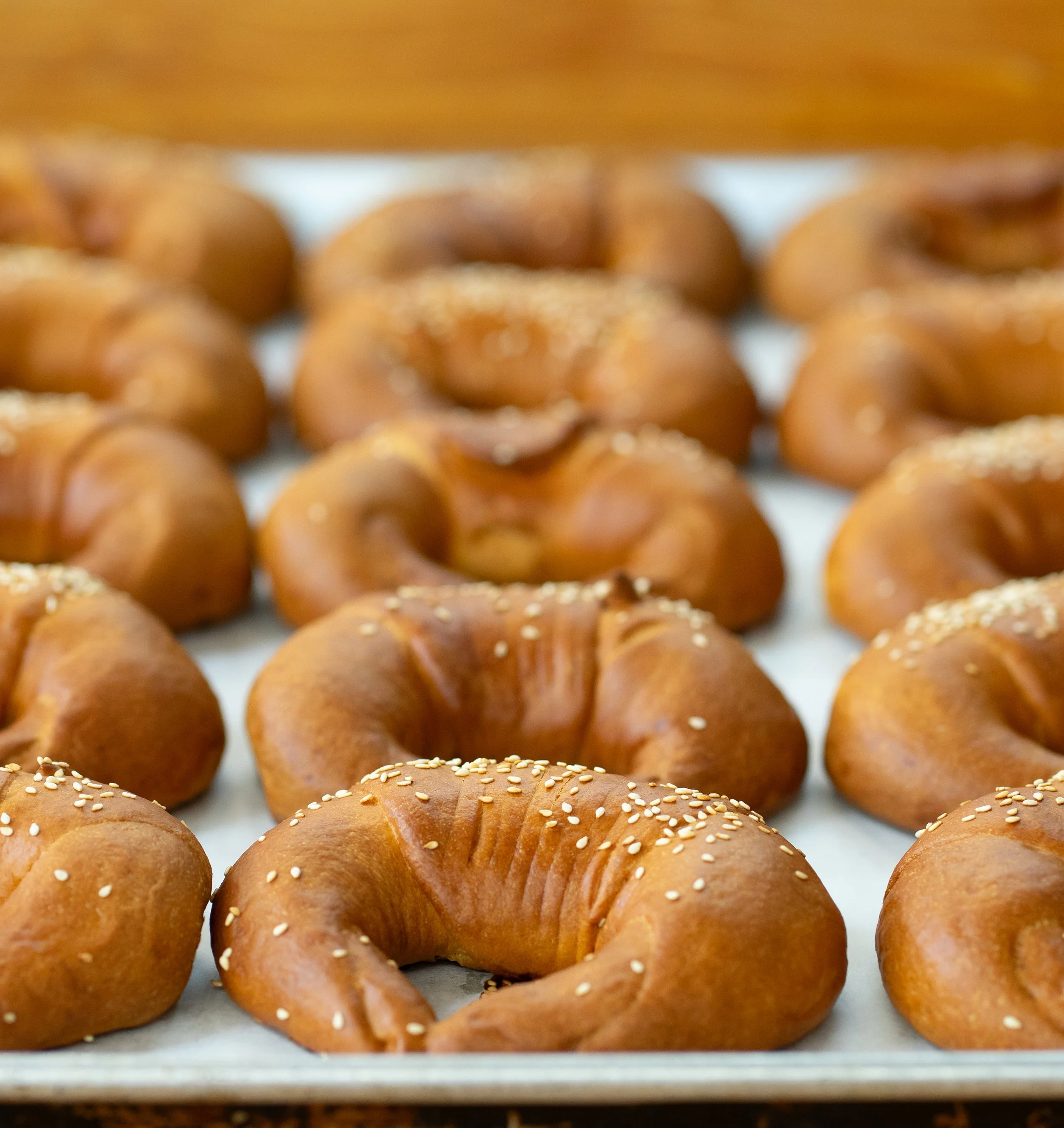 Fresh baked croissants sprinkled with sesame seeds on a baking sheet.