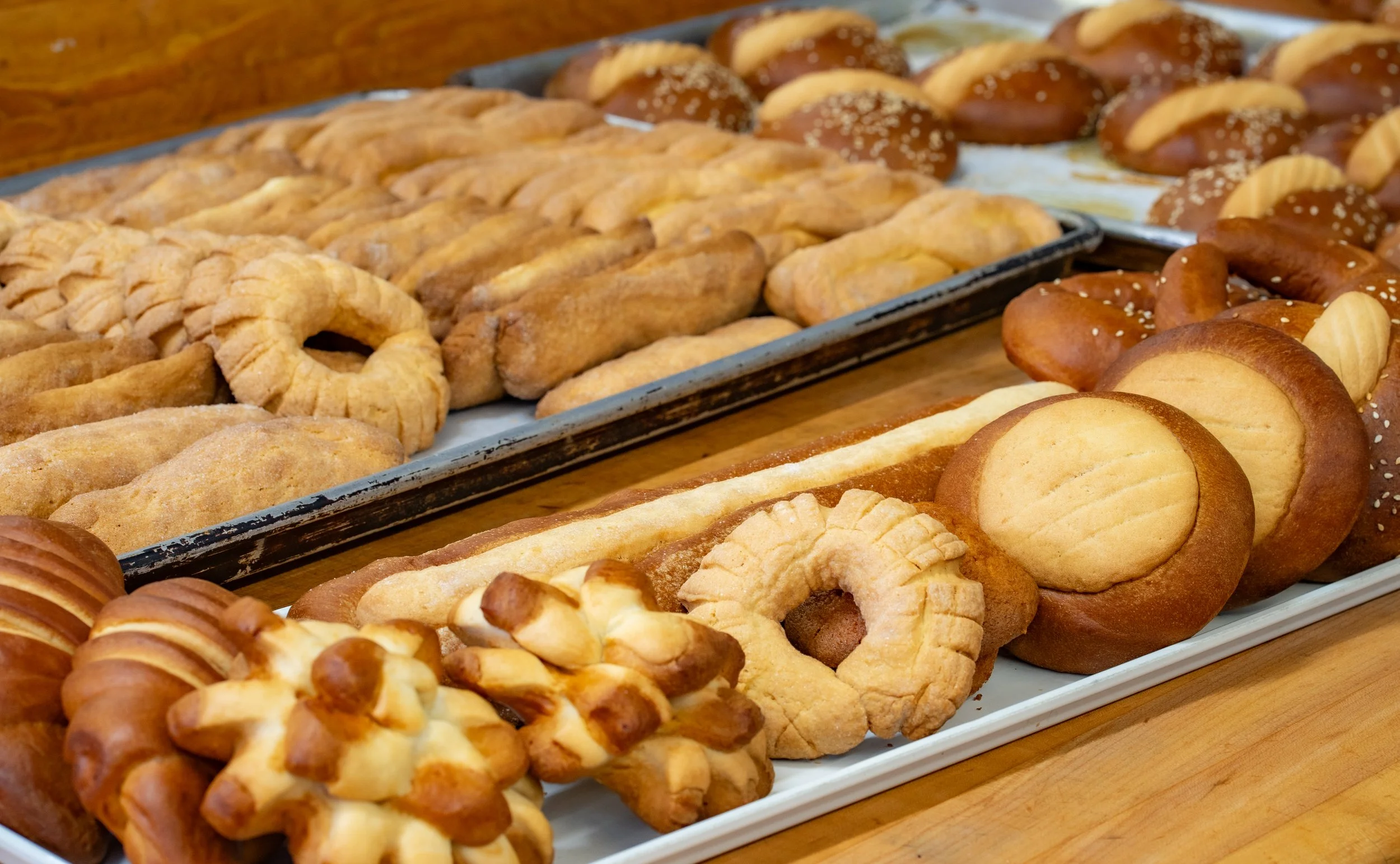Various baked pastries and cookies on trays, including pretzels and sweet buns.