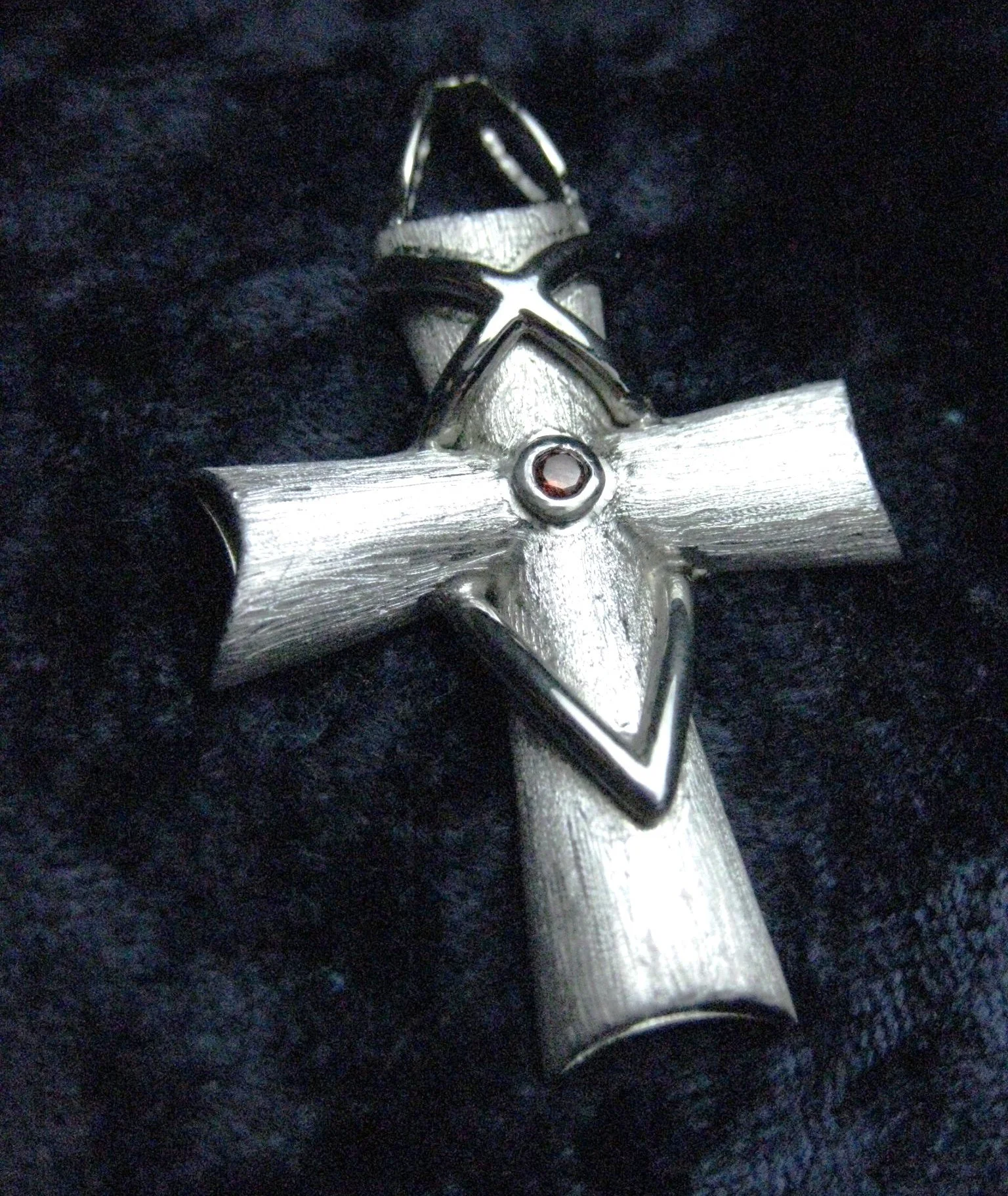 Close-up of a brushed finished silver cross pendant. 