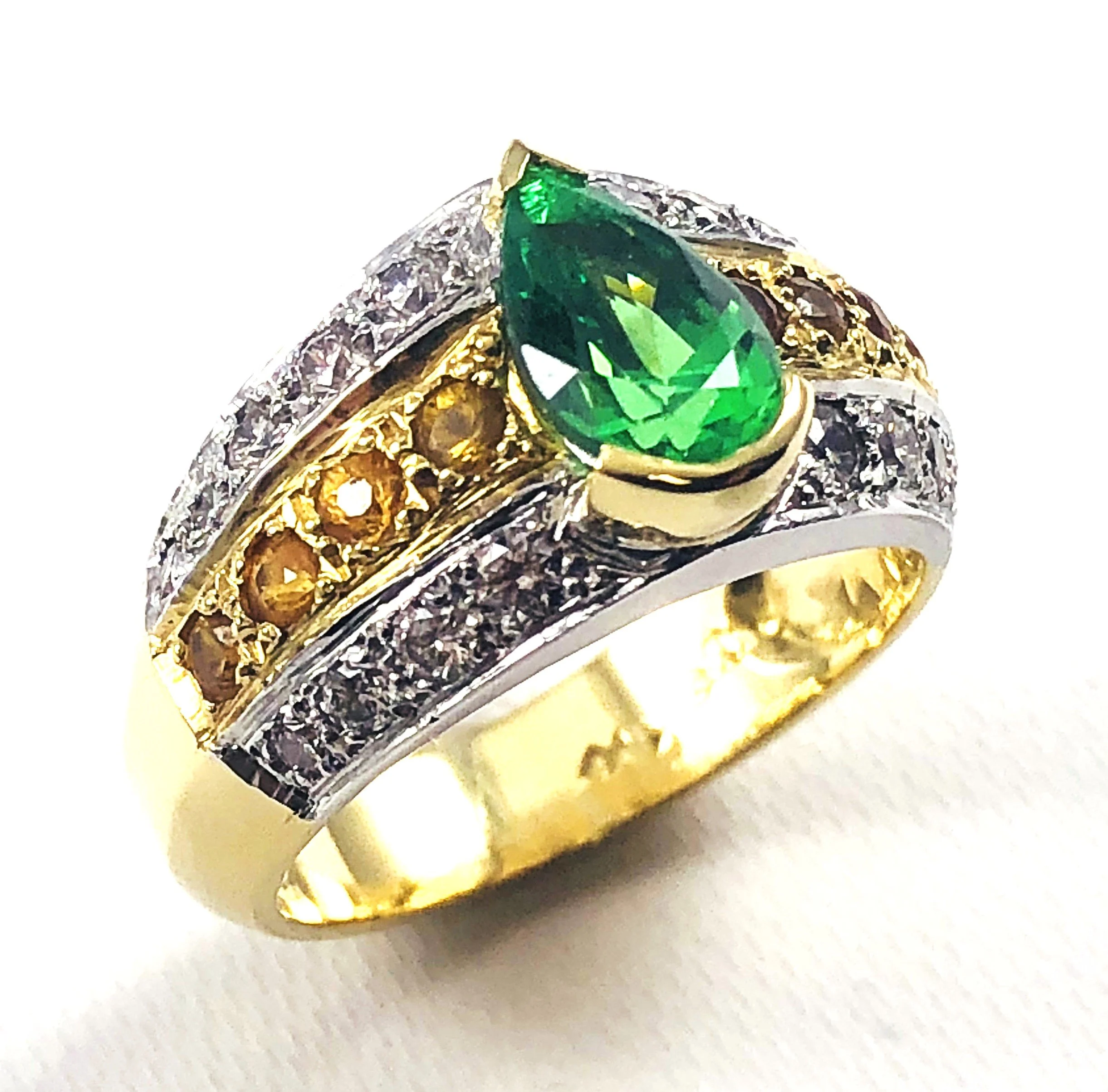 Close-up of a gold and silver ring with a large teardrop-shaped tsavorite garnet gemstone and smaller diamonds.